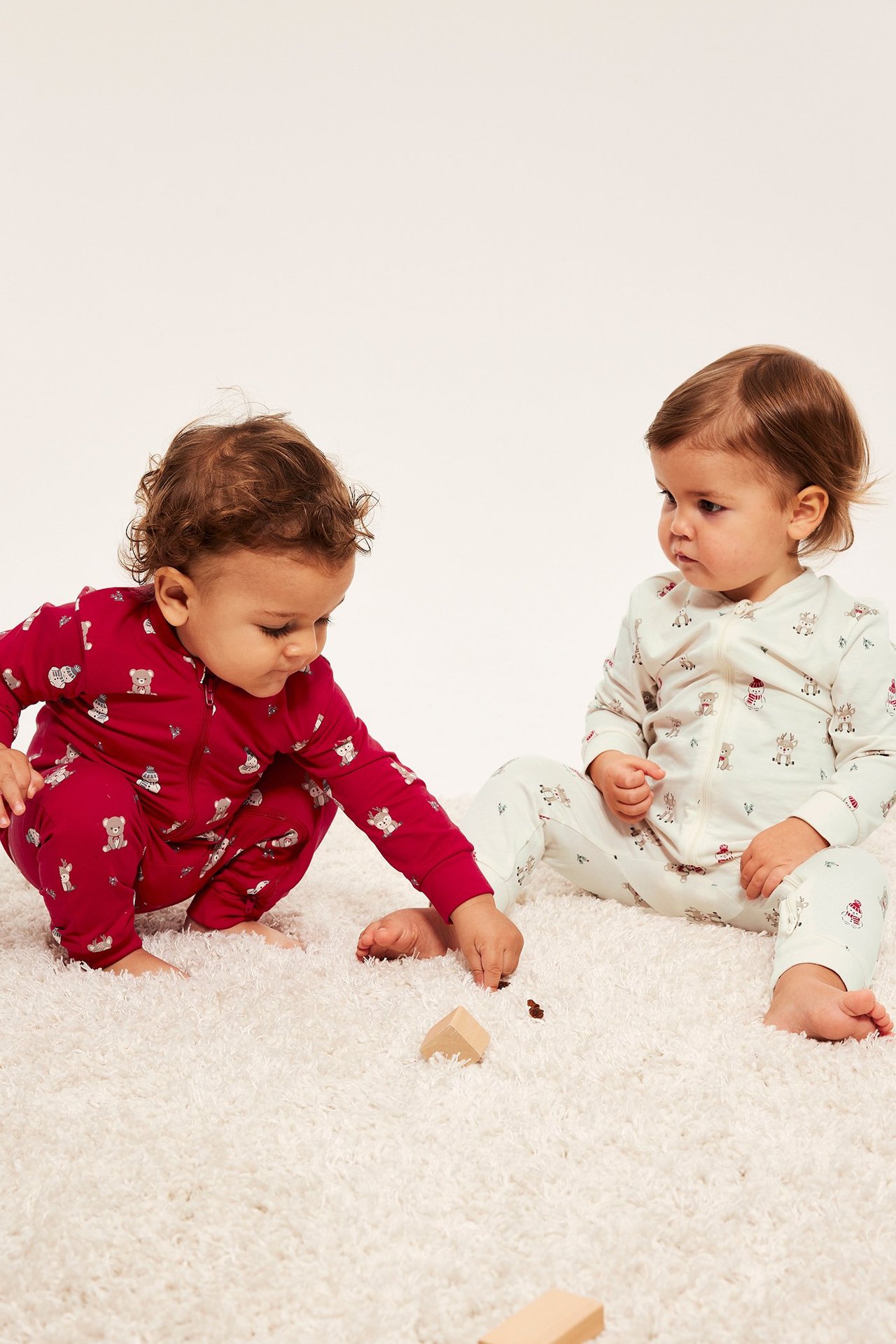 To baby piké med 2-veis glidelås, offwhite med mønster, sittende barn foran.