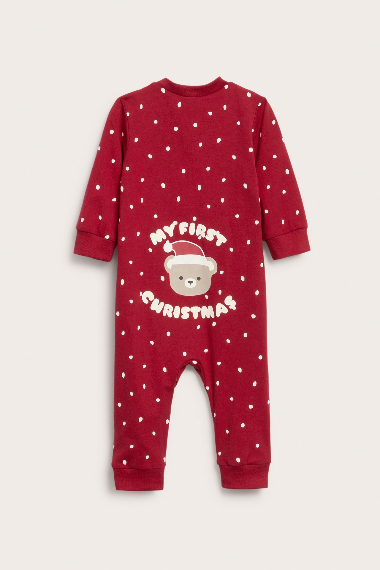 Punainen vauvan pitkähihainen potkupuku valkoisilla pilkuilla ja "My First Christmas" -karhupainatuksella, takaapäin.
