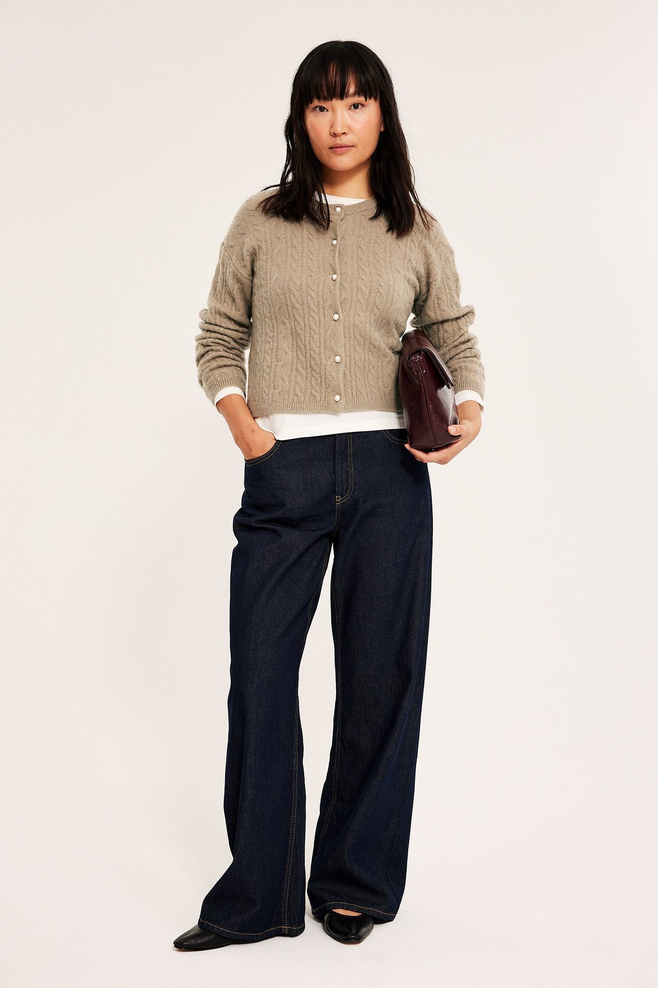 Tummansininen tikkikäsine, avoinna valkoisen T-paidan päällä, sivulta katsottuna.