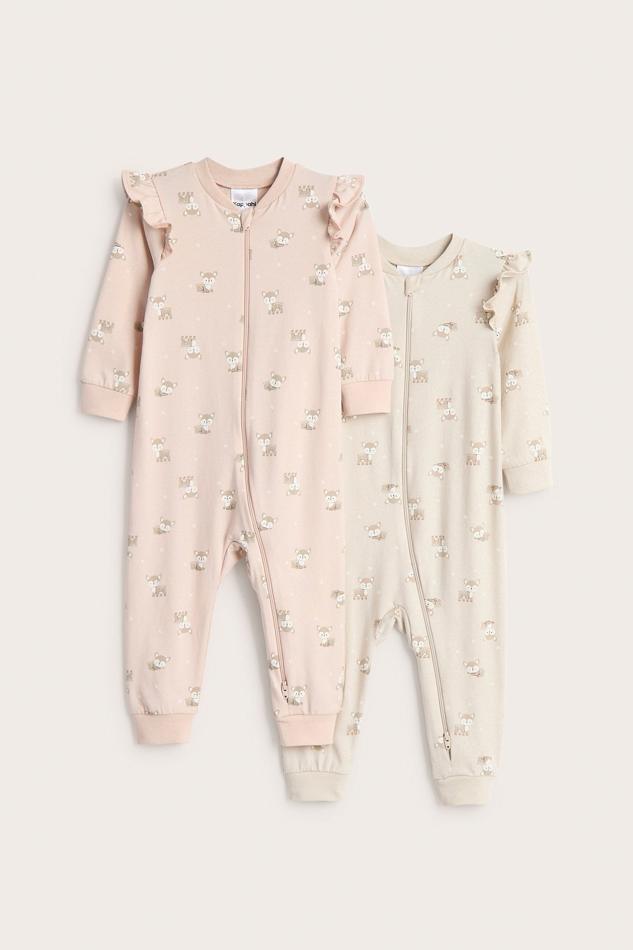 Framifrån: två babyrompers, en rosa och en beige mönstrad med volang på axlarna och tvåvägsdragkedja.