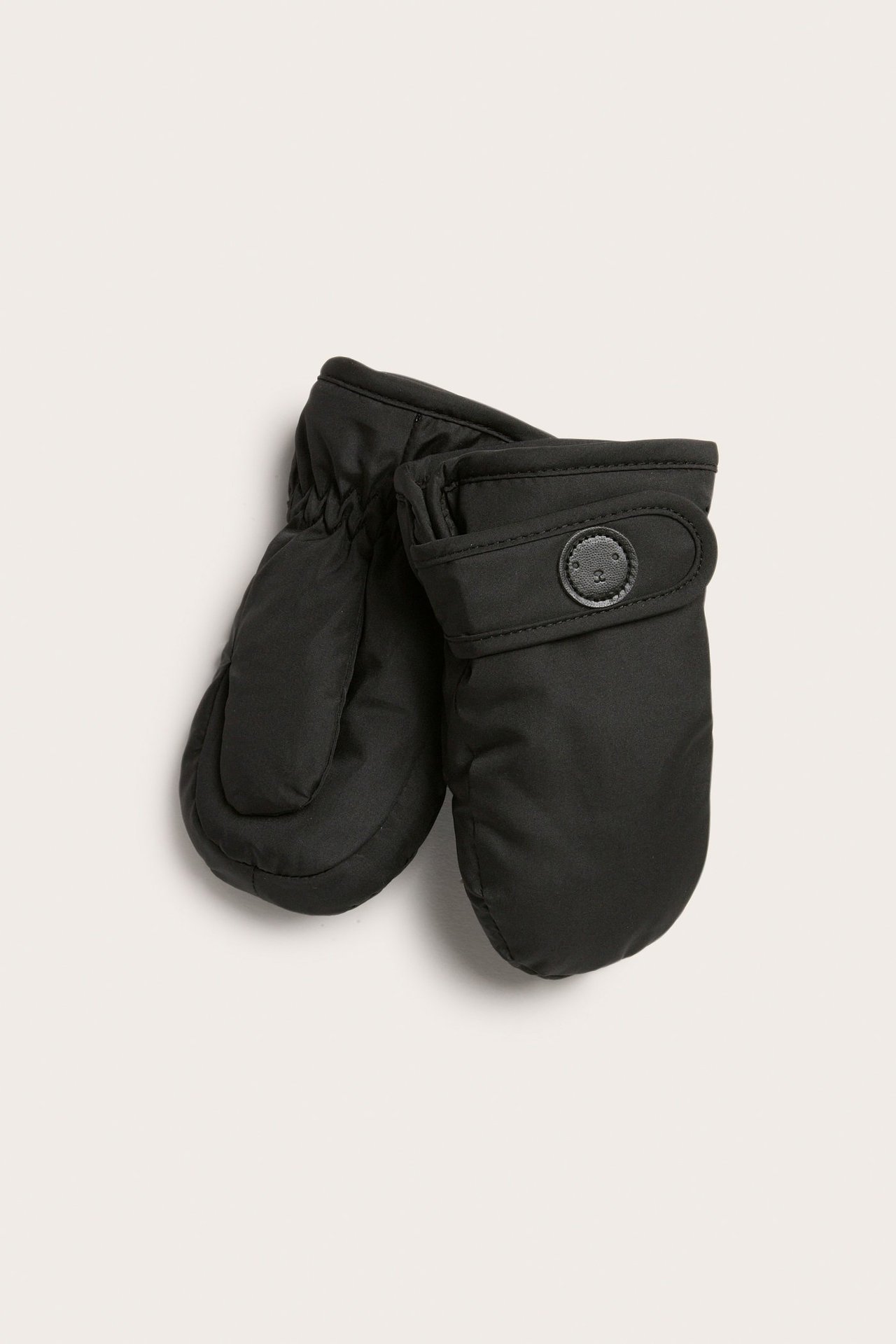 Lähikuva mustista vettähylkivistä vauvan lapasista, joissa on etuhihna ja nappiyksityiskohta.