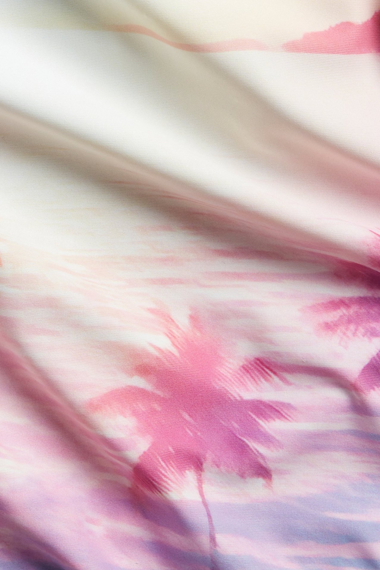 Lähikuva vaaleanpunaisesta uimapukukankaasta, jossa on purppura ja vaaleanpunainen palmukuvio.