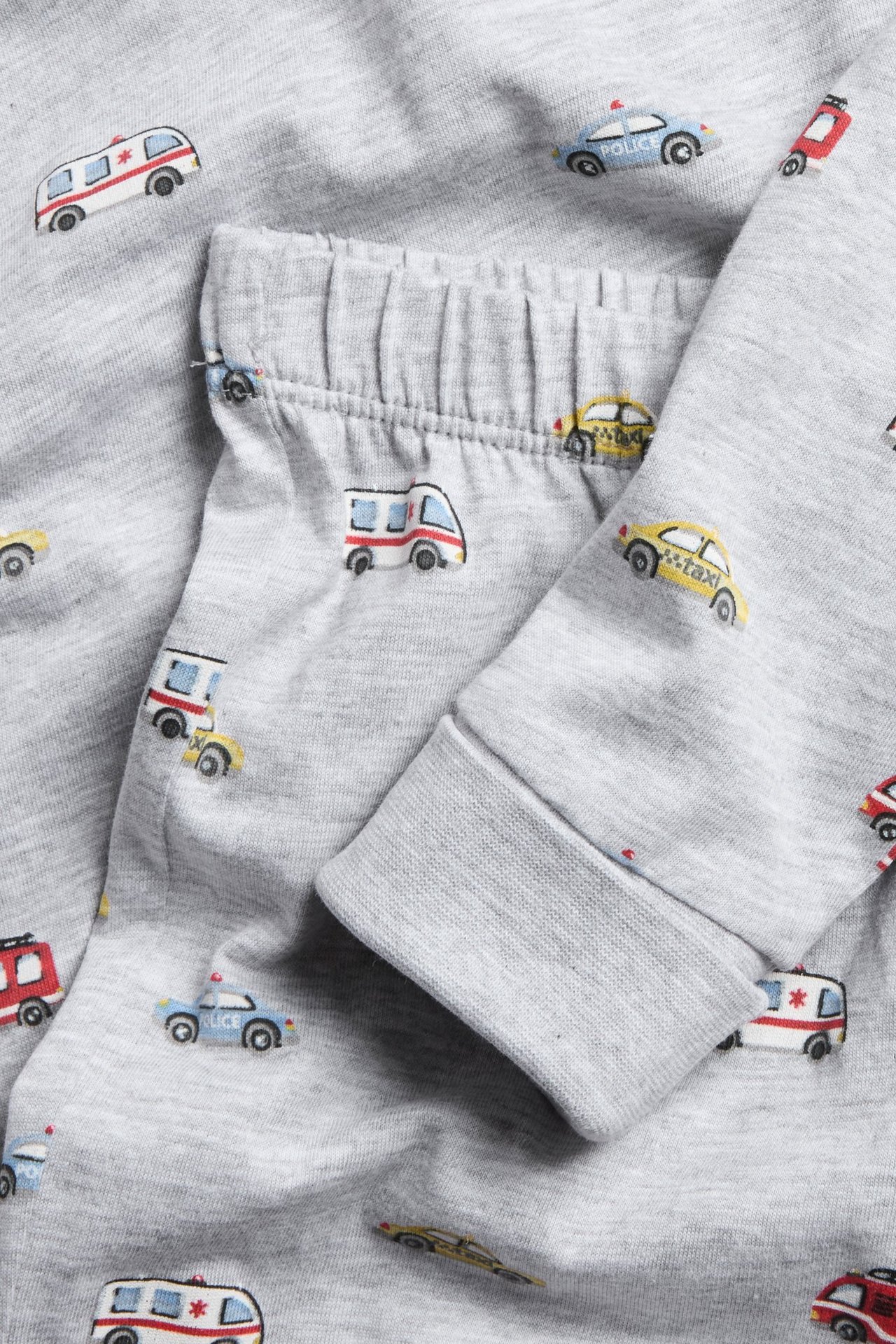 Pitkähihainen harmaa pyjama, pieni ambulans- ja poliisiautokuvio, ribbiset hihansuut.