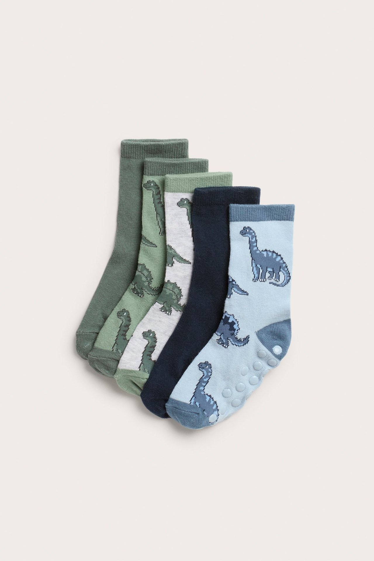 Edestä, viisi paria lasten sukkia: vihreät, harmaat, siniset, dinosauruskuvioilla ja liukuestenastoilla.