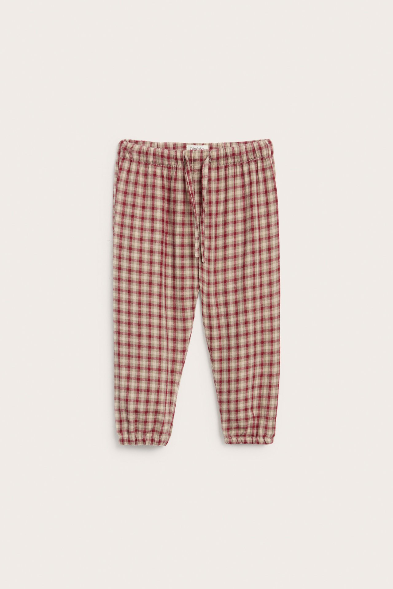 Front: Barns røde og beige rutete bomullsbukser med elastisk midje og snøring.
