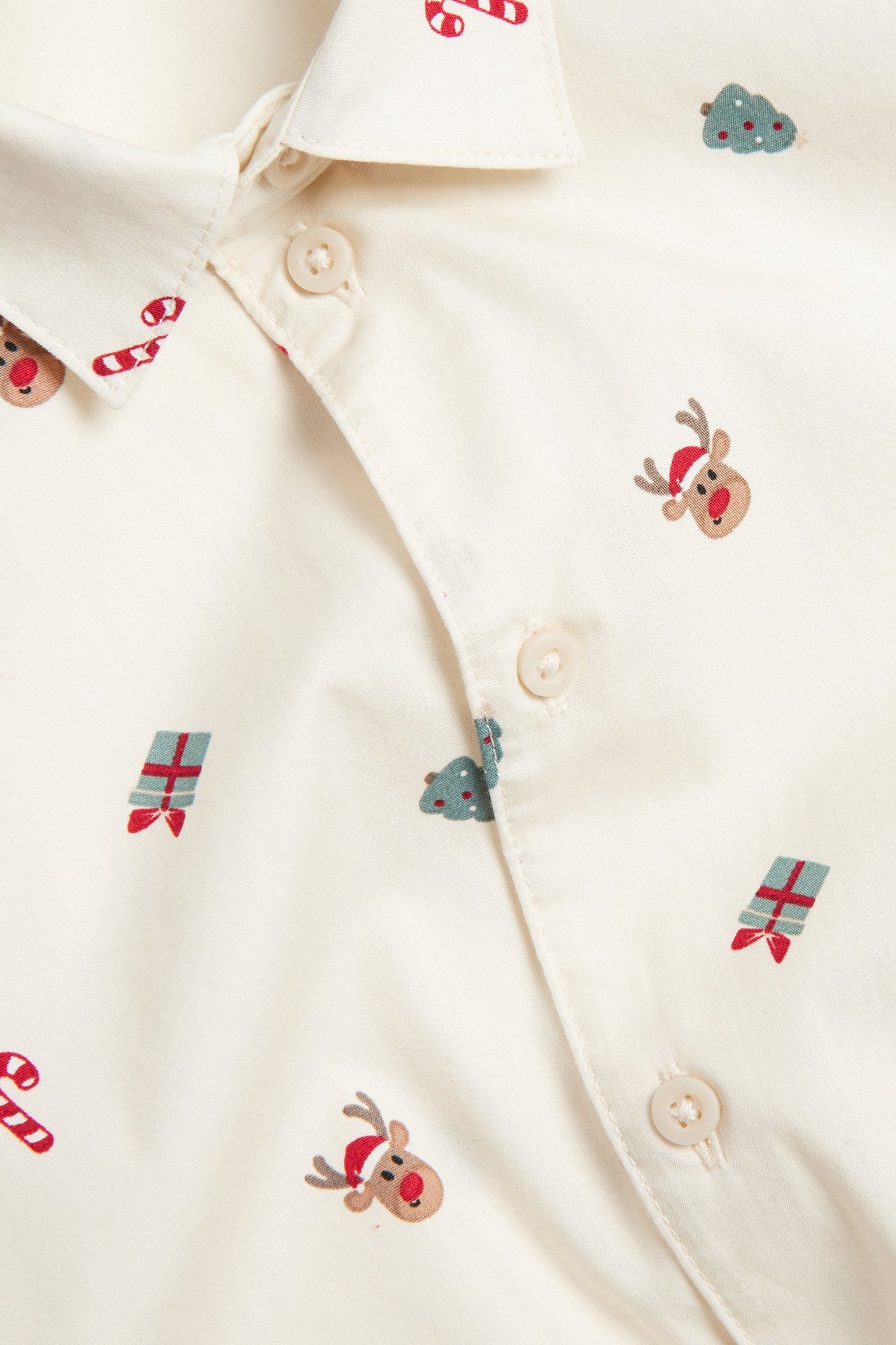 Zbliżenie beżowej koszuli bawełnianej z bożonarodzeniowym wzorem i zapięciem na guziki.