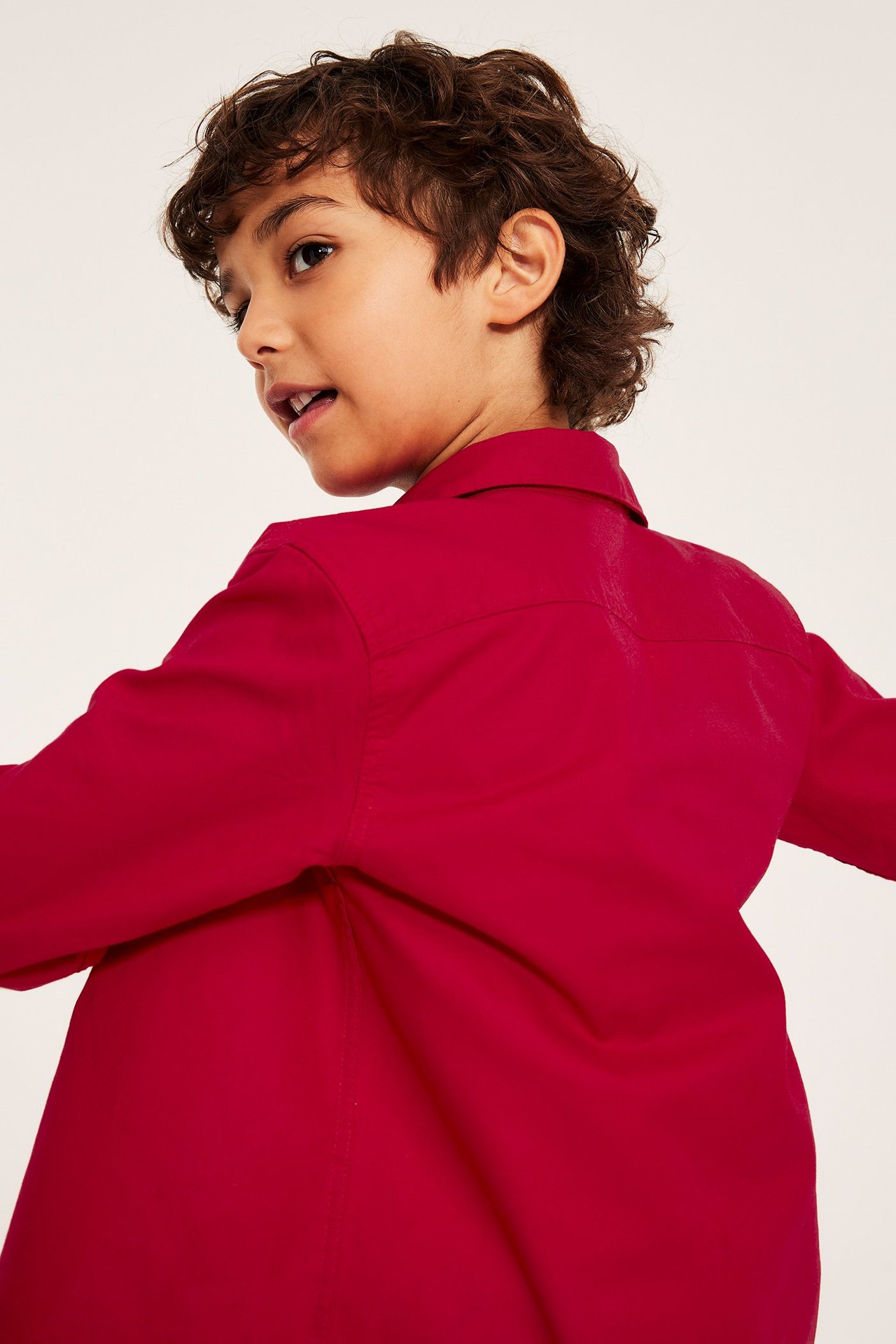 Lapsipoika punaisessa oxford-paidassa kauluksella, pitkähiha- ja yksivärinen, puuvillainen.