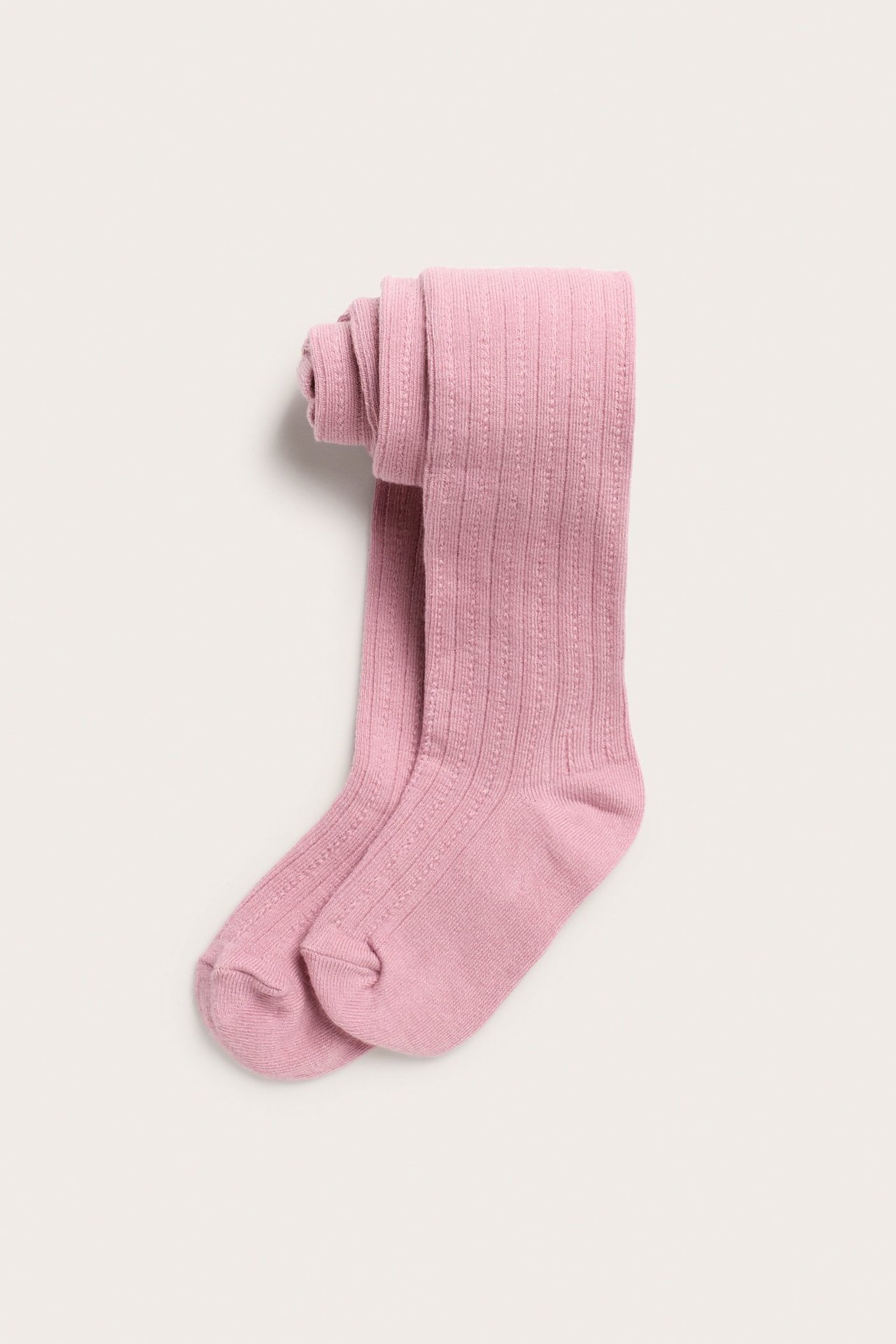 Ylhäältä näkymä taitetuista vaaleanpunaisista lasten sukkahousuista, joissa on neulottu kuvio.