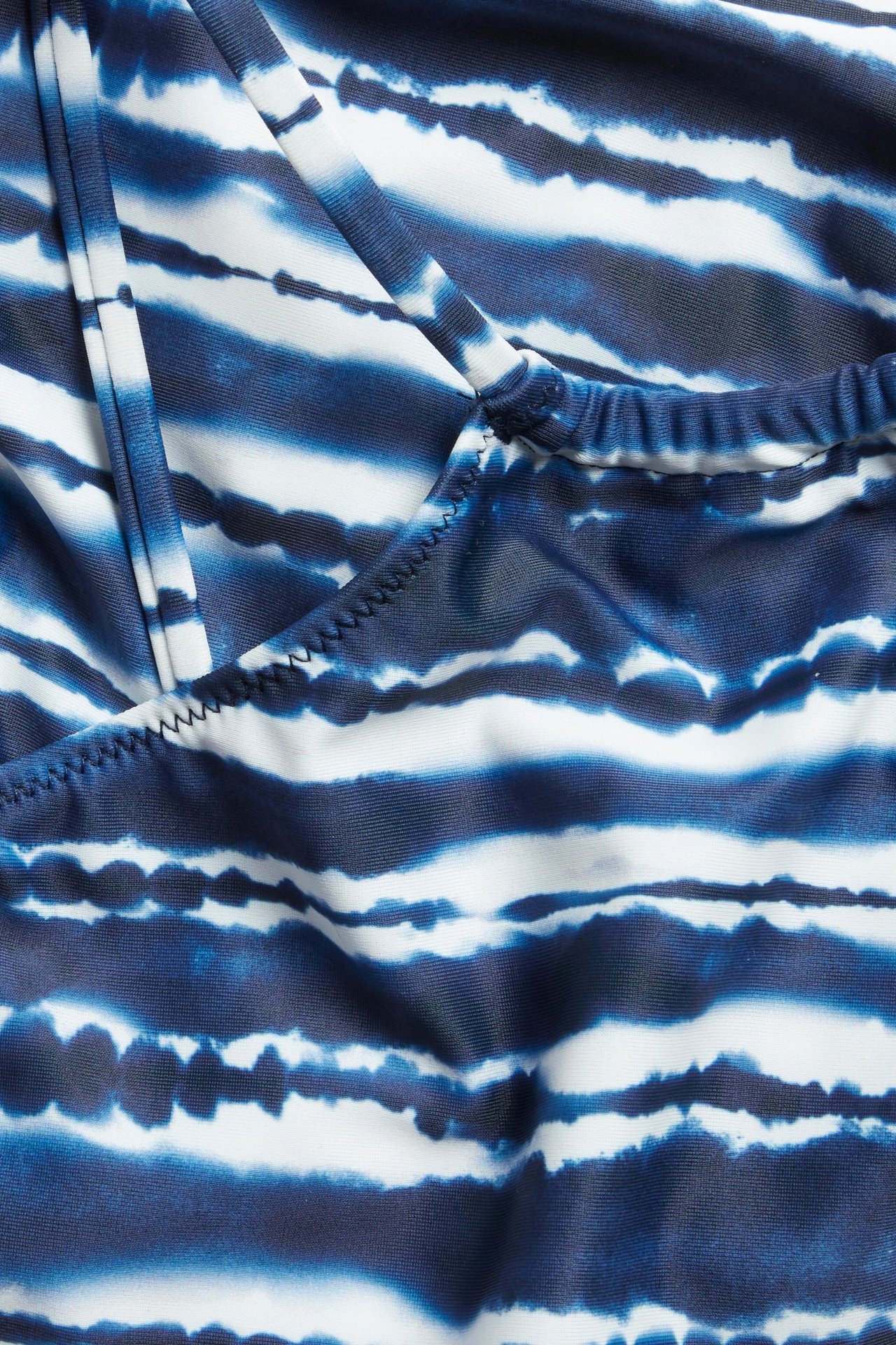 Lähikuva edestä sinivalkoisesta kuviollisesta bikinin yläosasta ristikkäisillä olkaimilla.