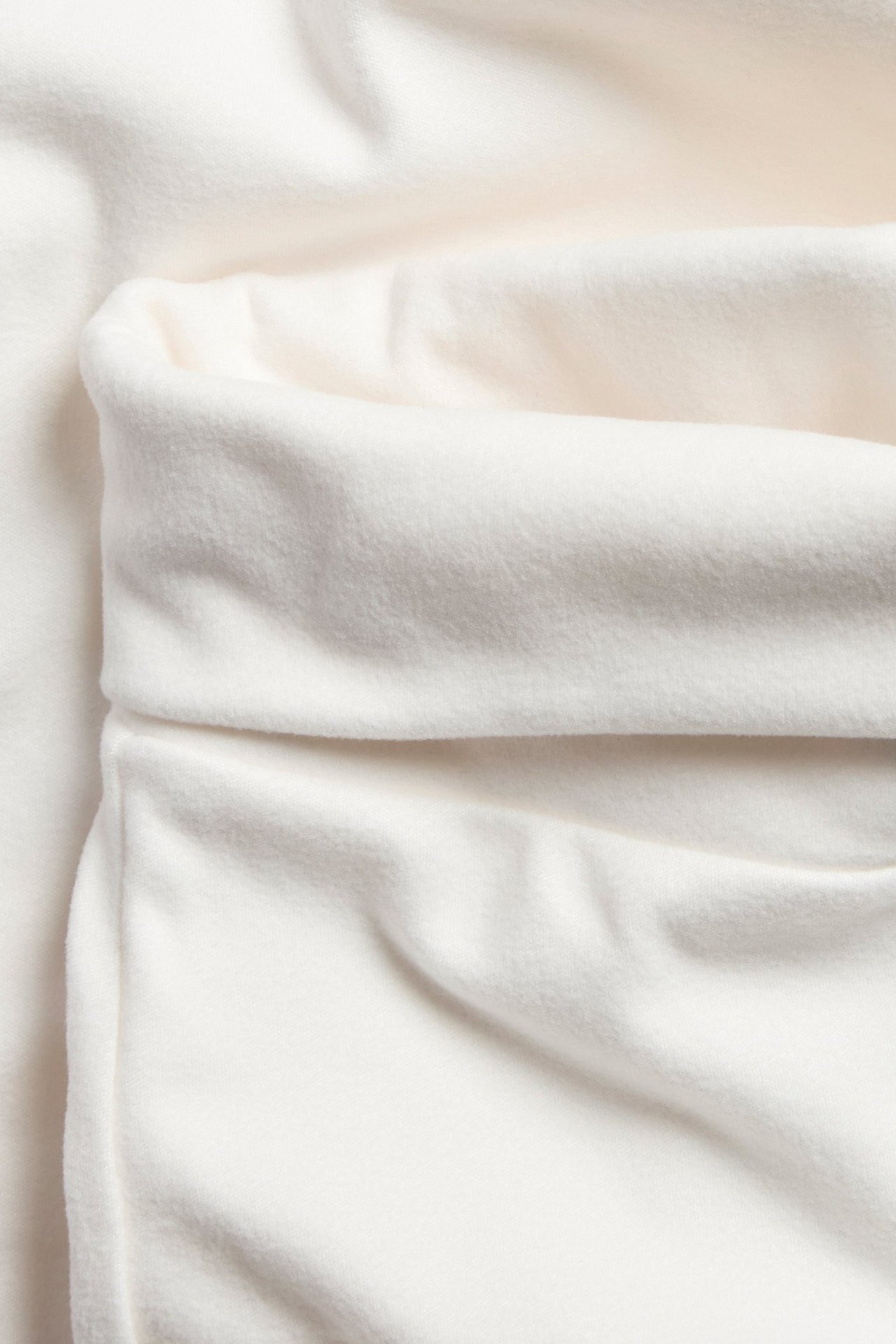 Zbliżenie na ecru ciepłe rozszerzane spodnie do jogi, widać złożony pas i miękki materiał.