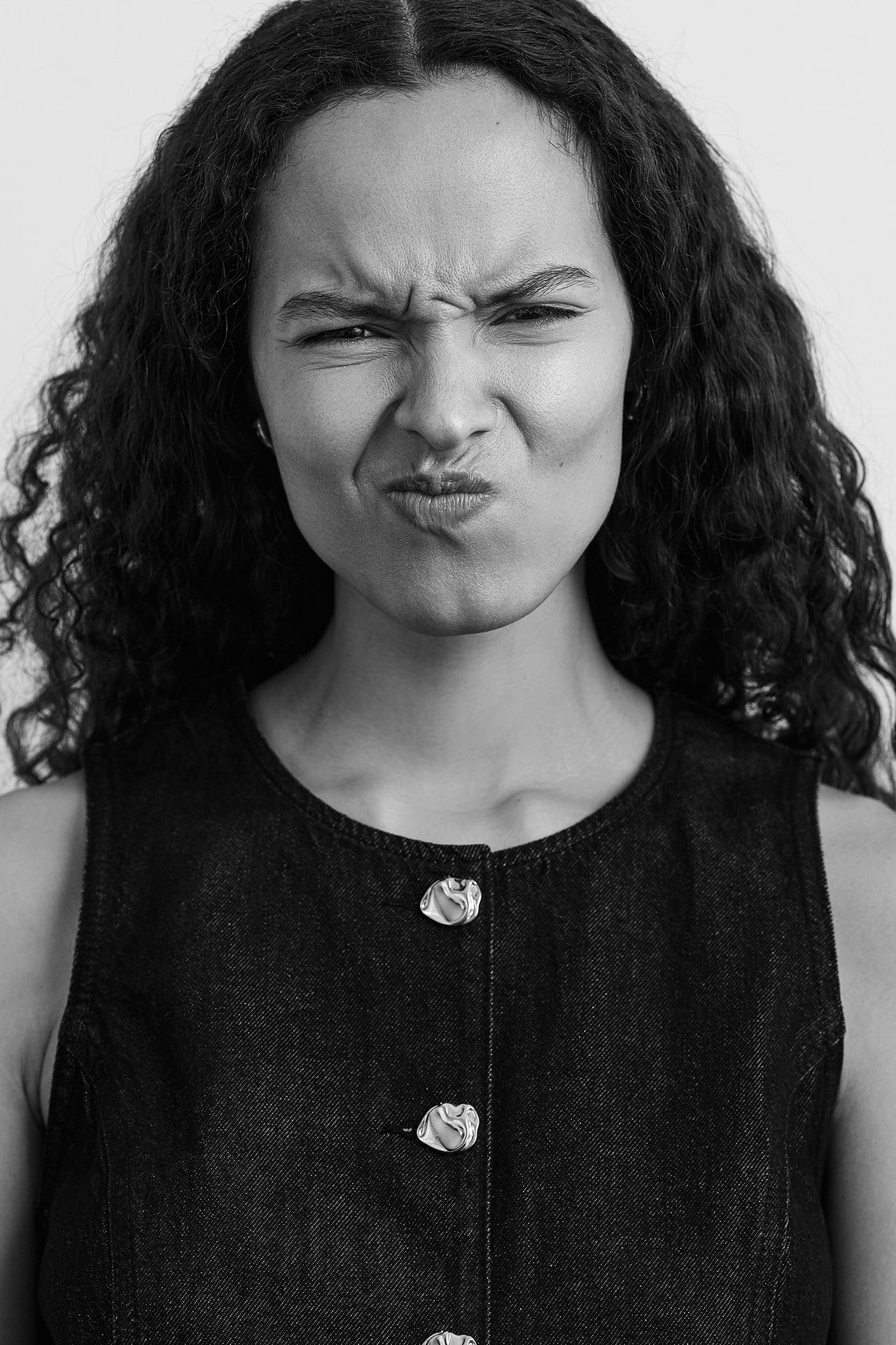 Lähikuva naisesta yllään vartalonmyötäinen tumma farkkuliivi orgaanisilla hopeanvärisillä napeilla.