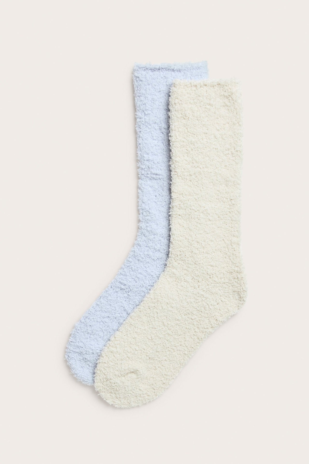 Ylhäältä: kaksi pörröistä yksiväristä sukkaa, yksi vaaleansininen ja yksi vaaleanbeige, pehmeää polyesteriä.