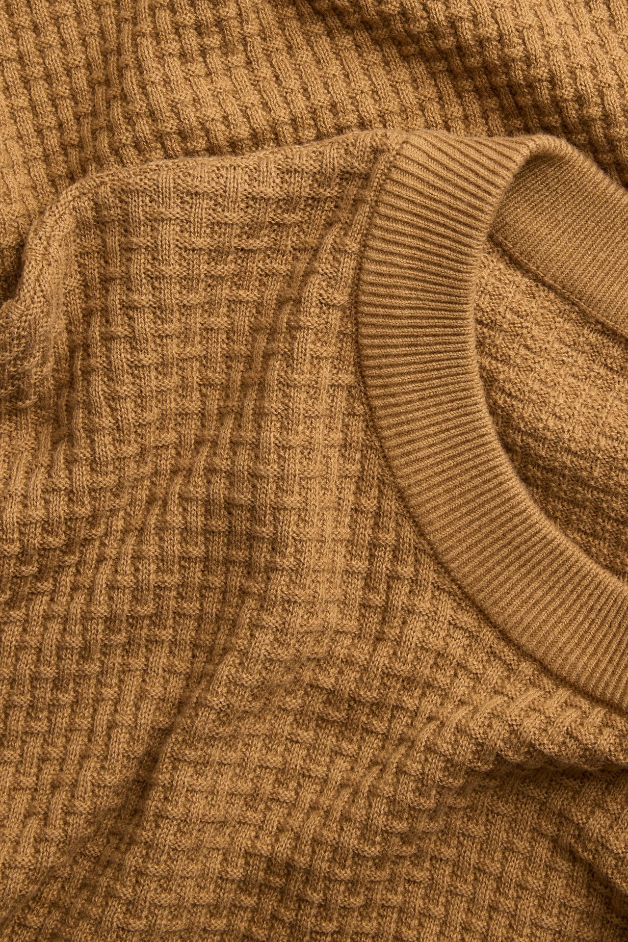 Zbliżenie na brązowy męski bawełniany sweter z teksturą i prążkowanym okrągłym dekoltem.