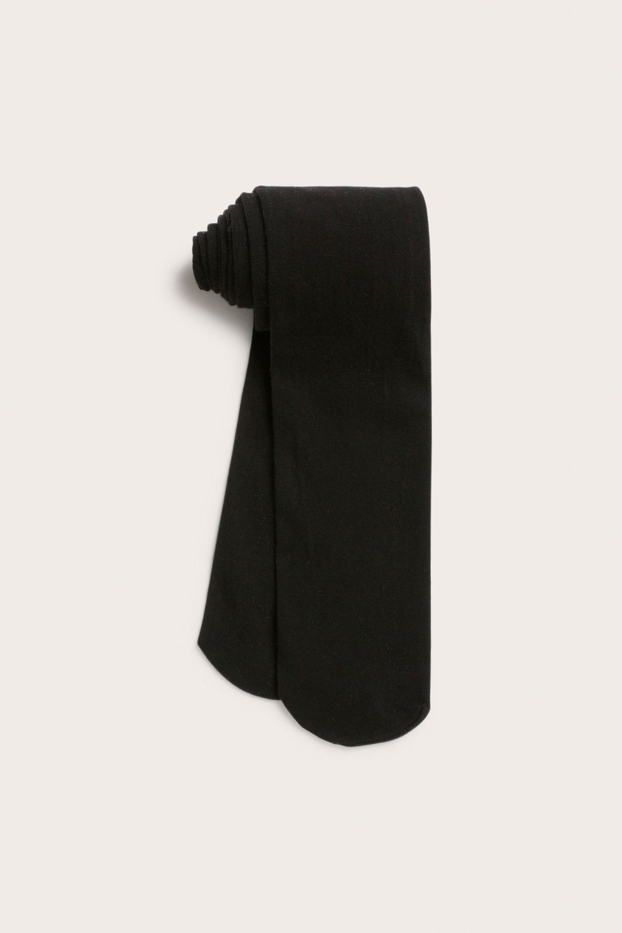 Uppifrån-vy av ett par svarta enfärgade strumpbyxor, vikta och rullade.