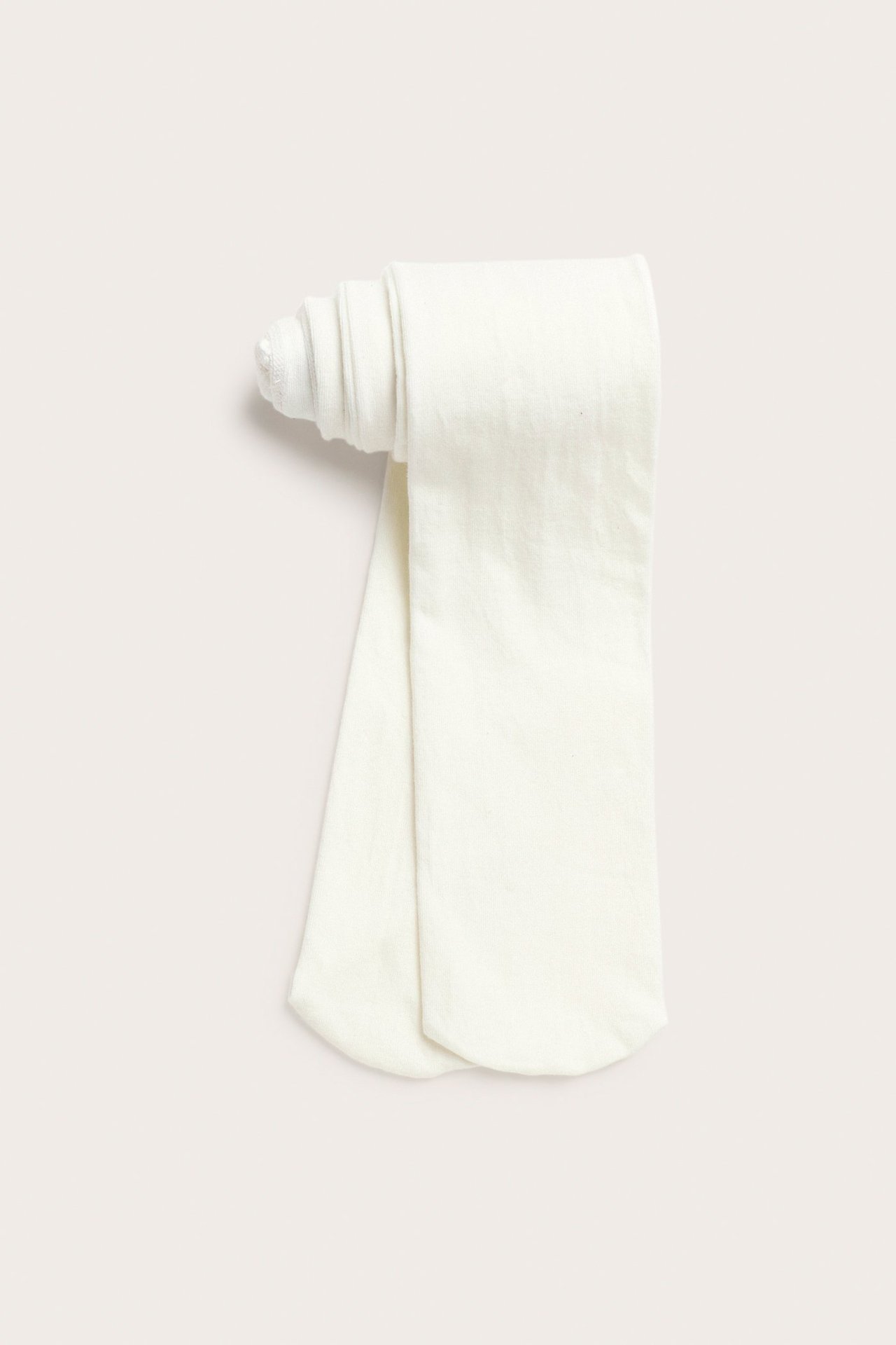 Ylhäältä kuvatut yksiväriset luonnonvalkoiset lasten sukkahousut, puuvillasekoitetta.