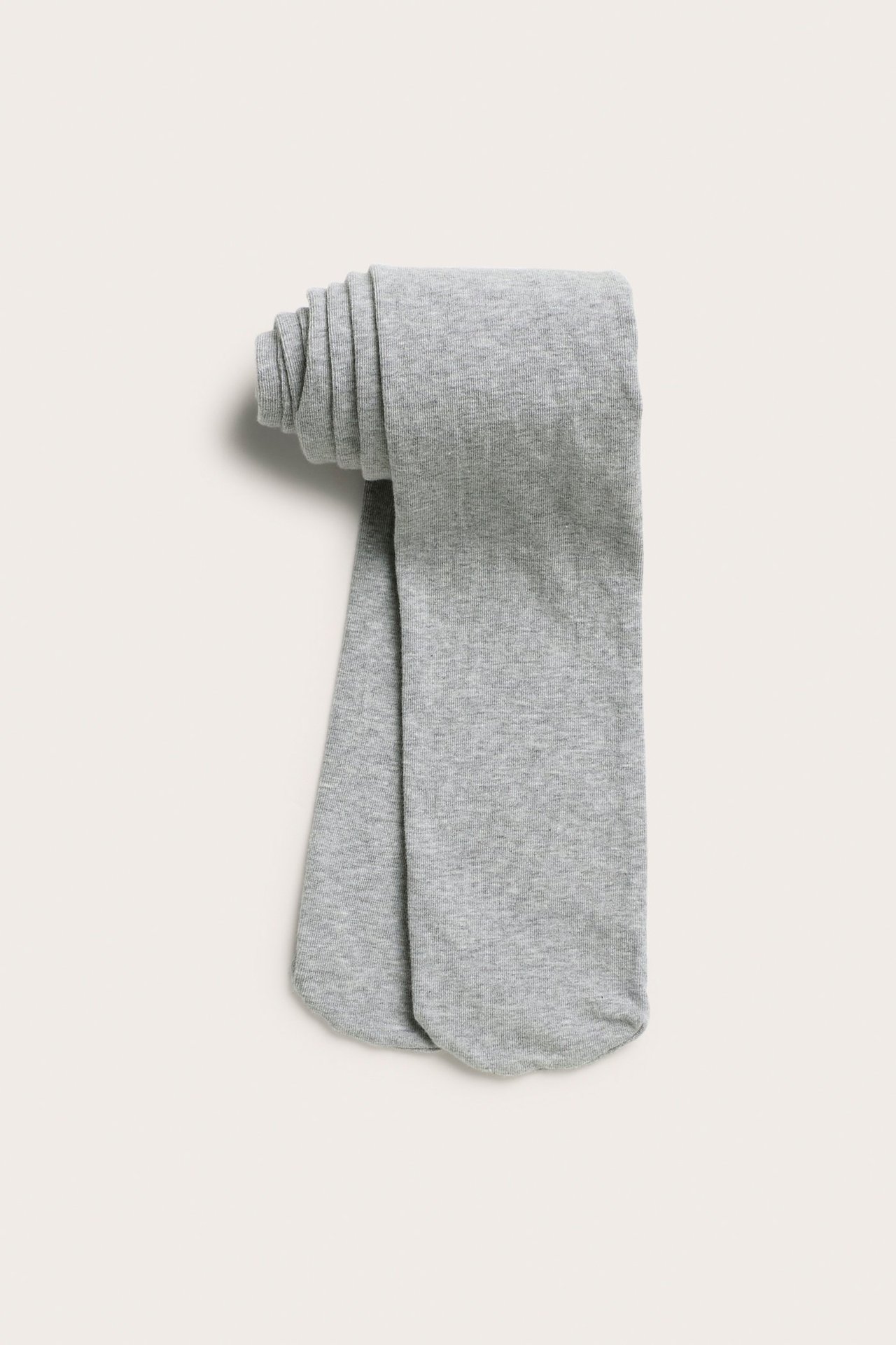 Ylhäältä näkymä vaaleanharmaista yksivärisistä lasten sukkahousuista, siististi taiteltuna.