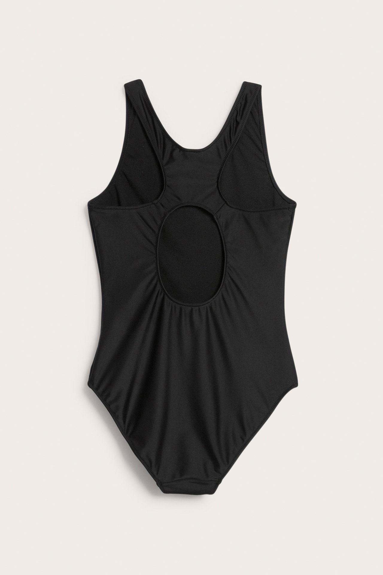 Selkäkuva yksivärisestä mustasta uimapuvusta leveämmillä olkaimilla ja pyöreällä leikkauksella takana.