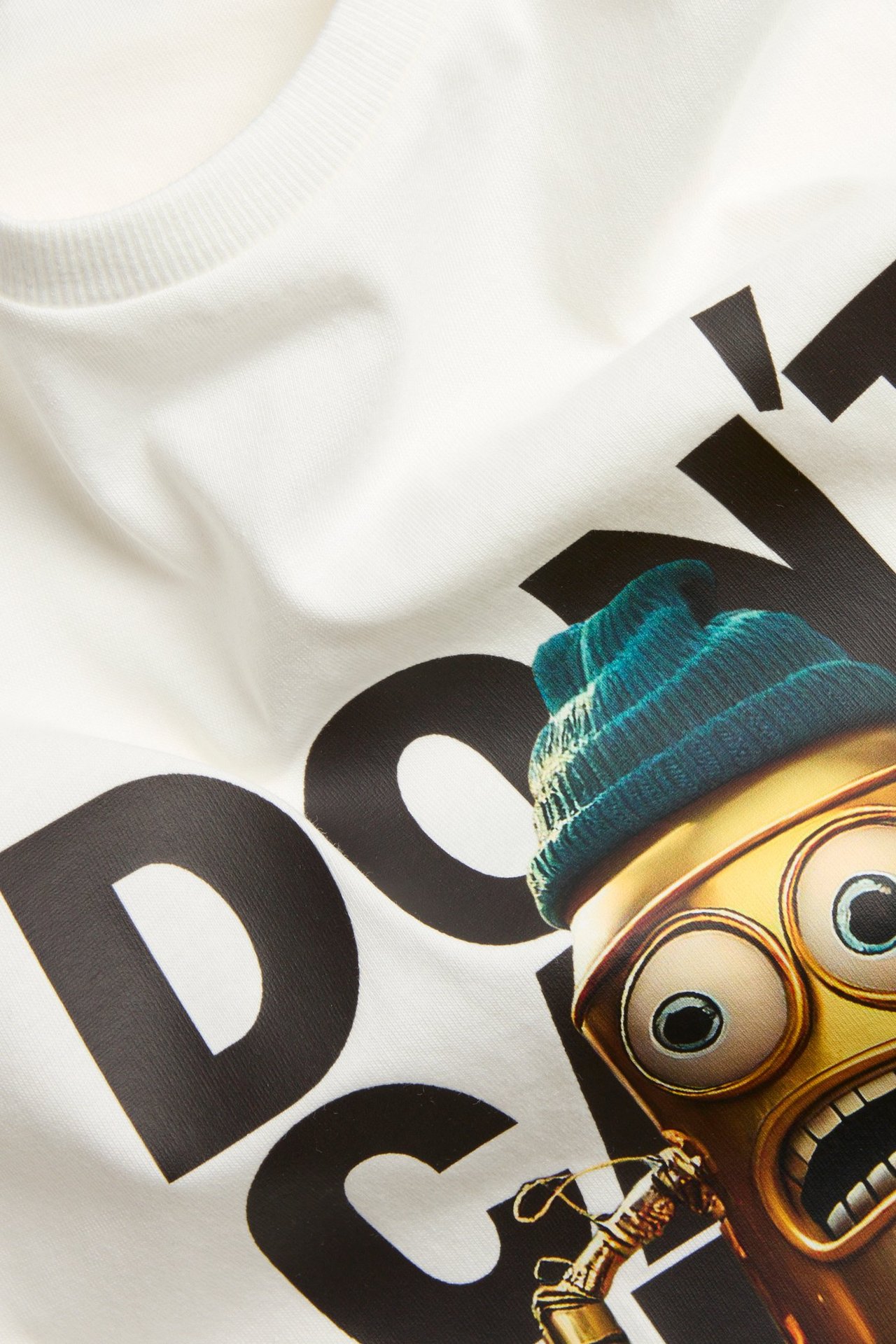 Zbliżenie: Biały bawełniany t-shirt z prążkowanym dekoltem i nadrukiem postaci z przodu.