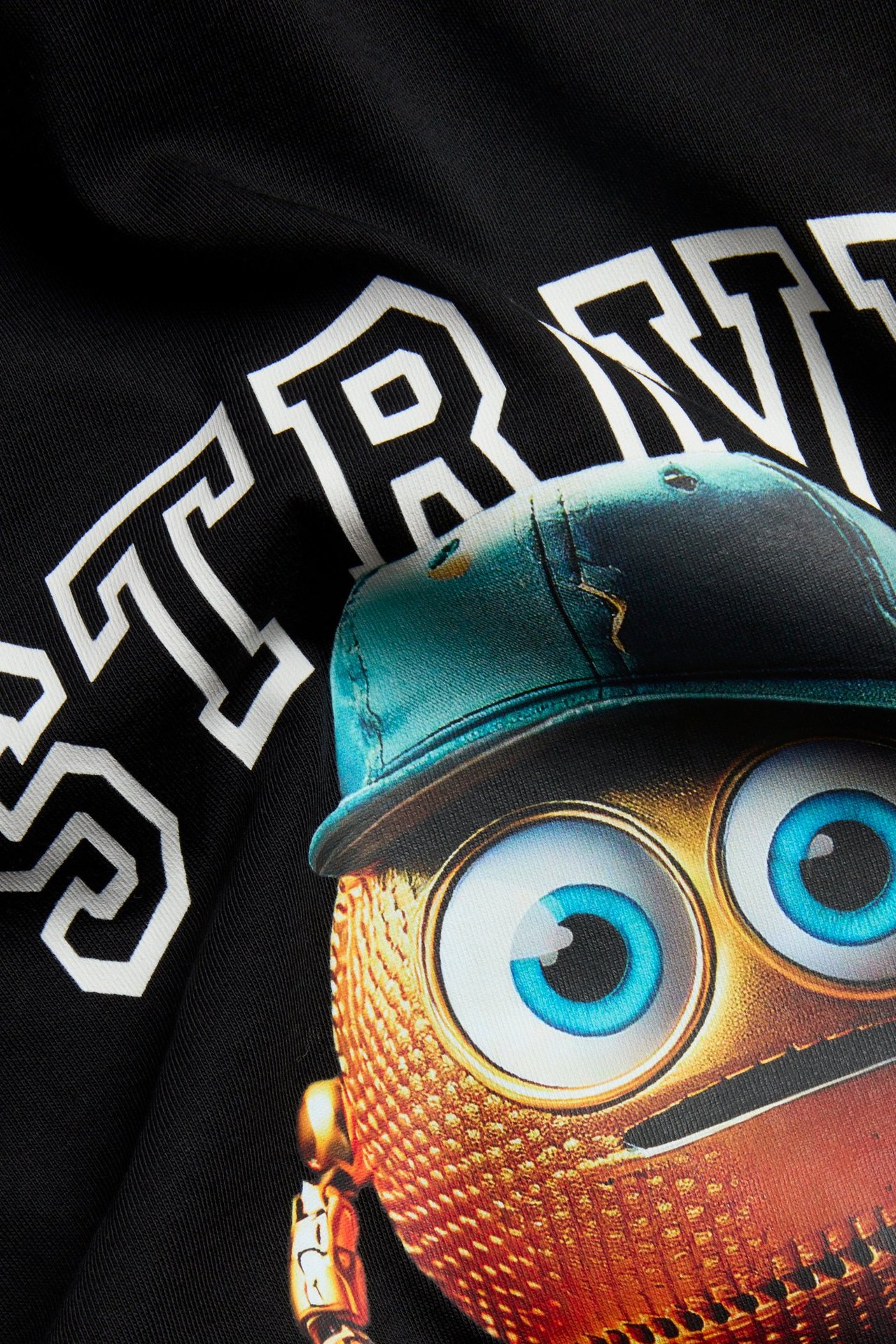 Zbliżenie na czarny bawełniany t-shirt dziecięcy z kolorowym nadrukiem postaci i białym tekstem z przodu.