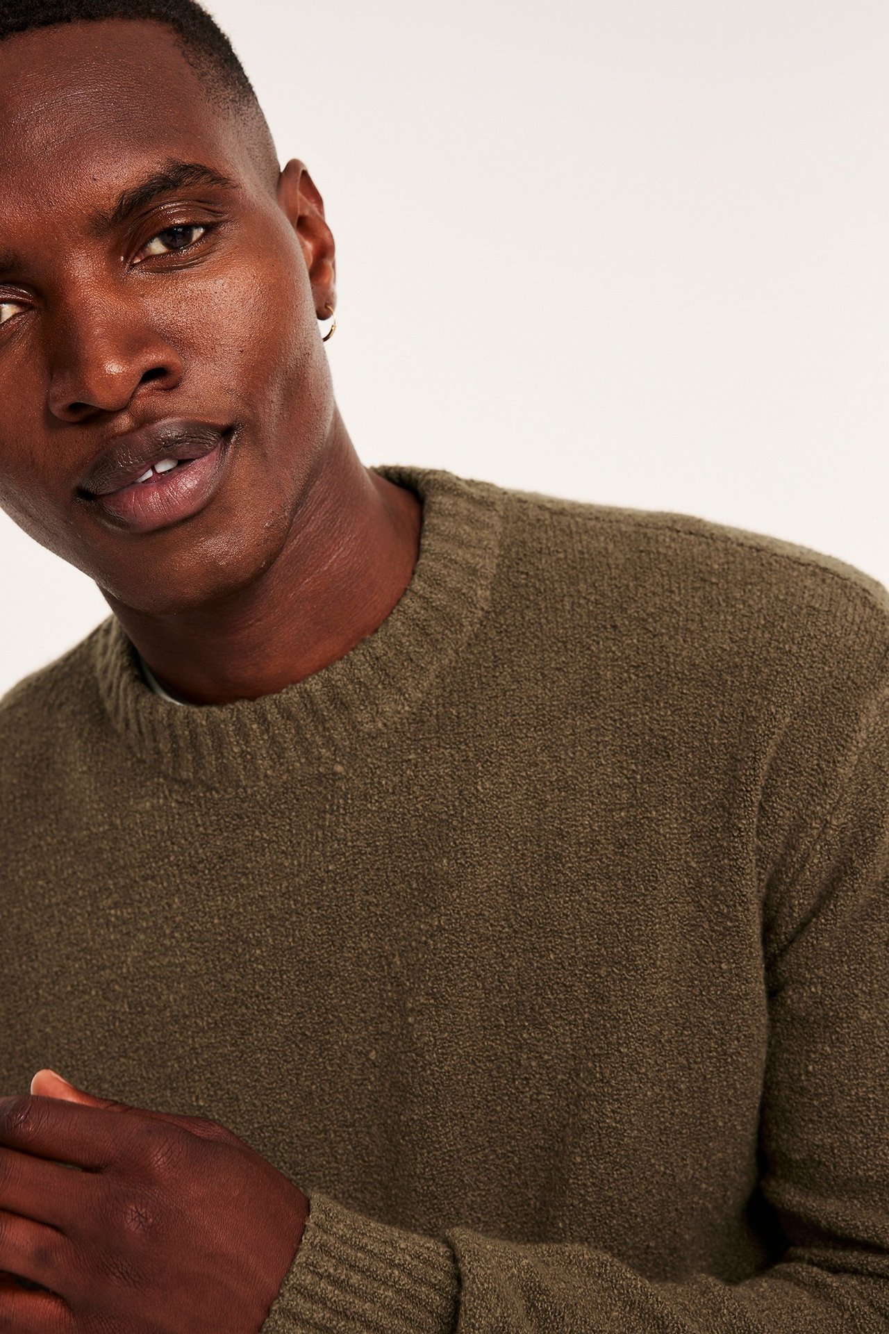 Nærbilde forfra av en mann i en teksturert mørkbrun strikkegenser med rund hals.