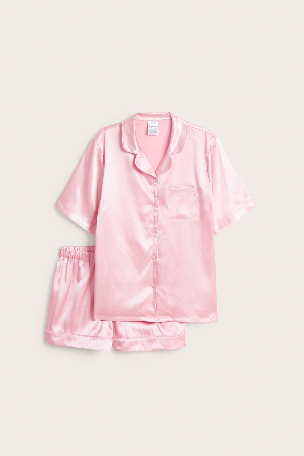 Edestä näkymä vaaleanpunaisesta satiinipyjamasetistä, jossa lyhythihainen nappipaita ja yhteensopivat shortsit.