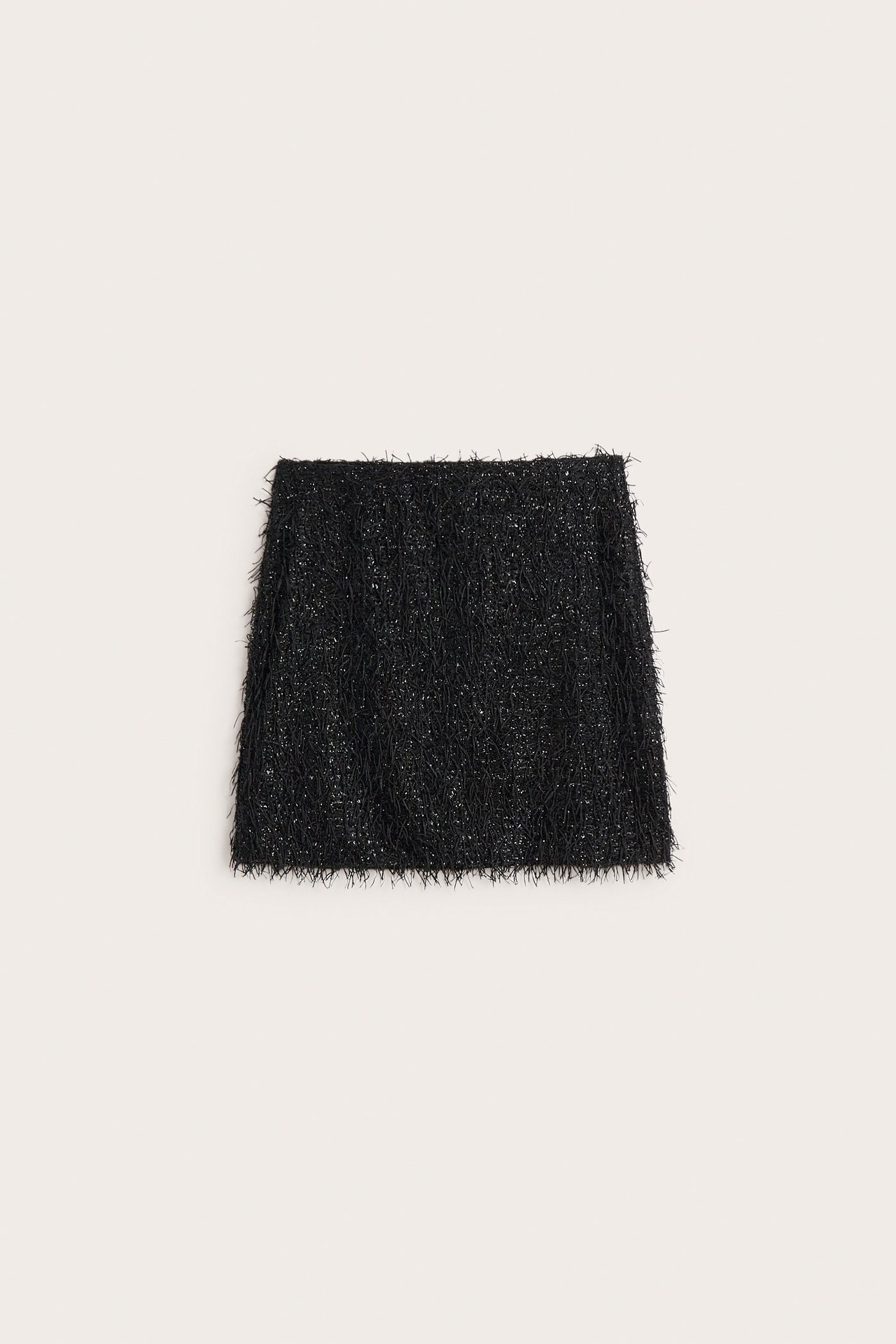 Framifrån: En svart kjol med heltäckande fransar.