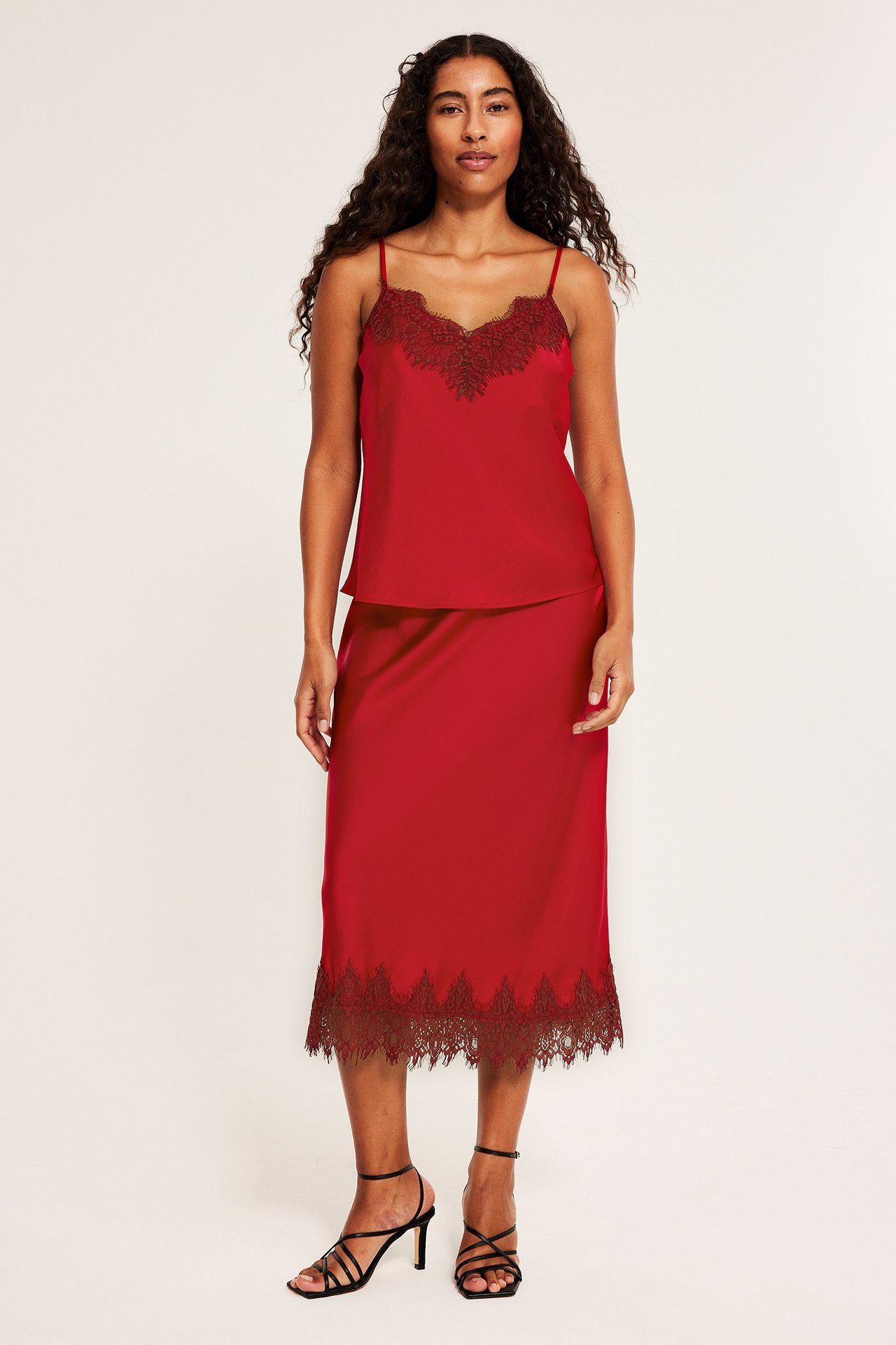 Punainen hame, pitsireunus, elastinen vyötärö, nainen, mustat korot, edestä.