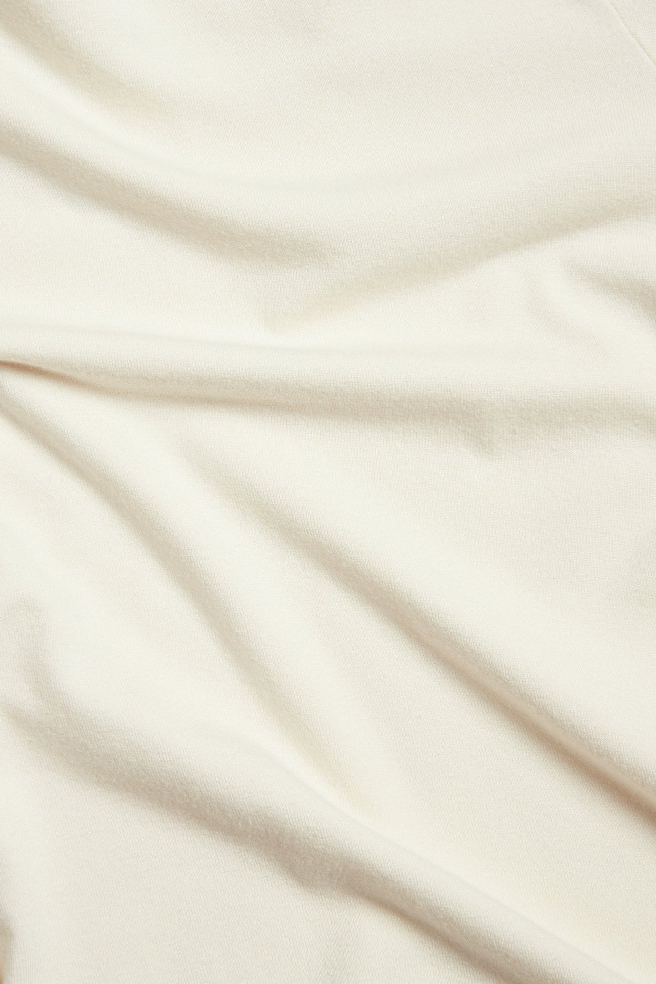 Zbliżenie tkaniny: damski kremowy, wiskozowy, długi top z golfem, jednolity, miękkie fałdy.