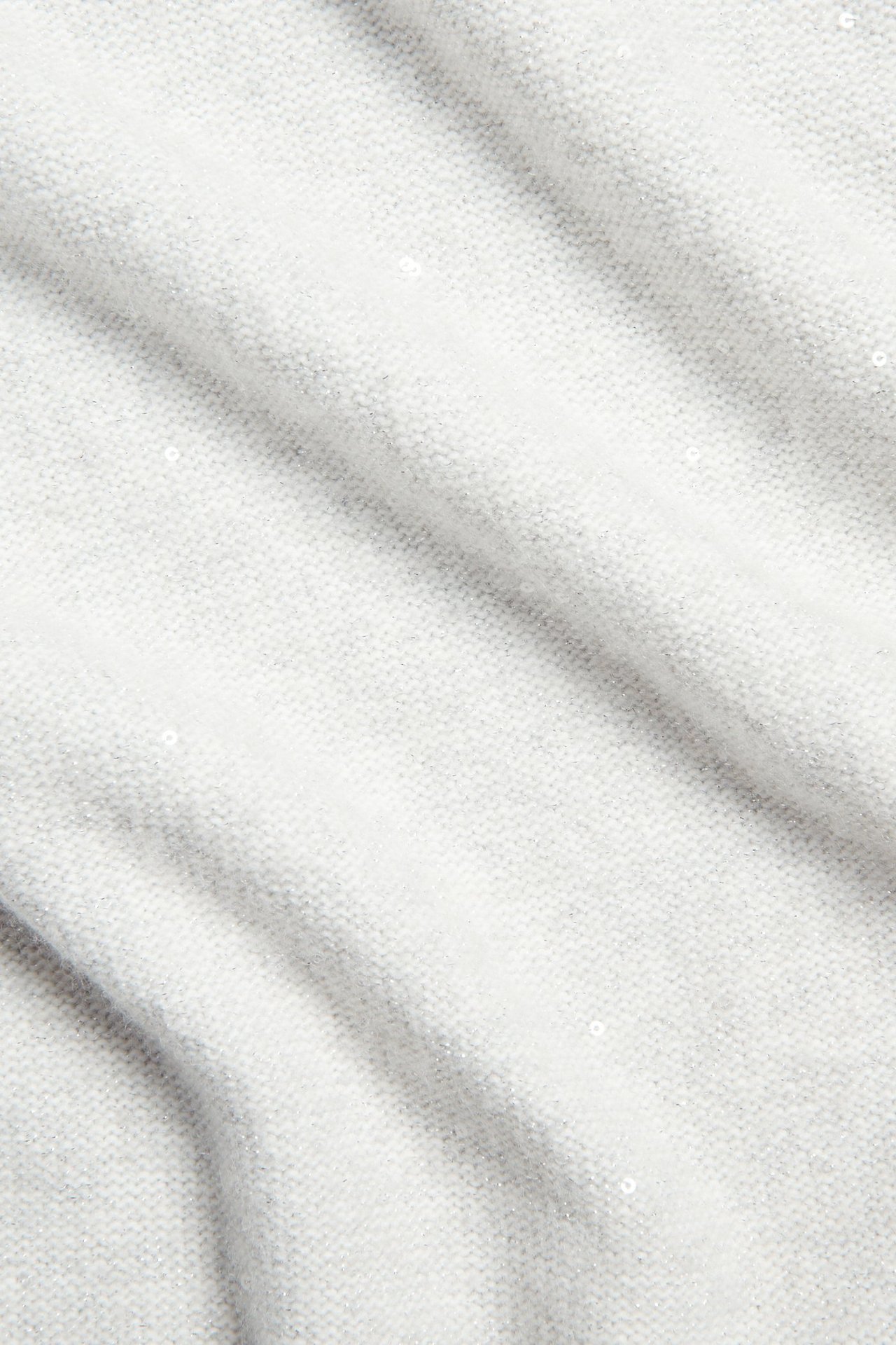 Zbliżenie na białą dzianinową sukienkę z małymi, subtelnymi cekinami i miękką fakturą.