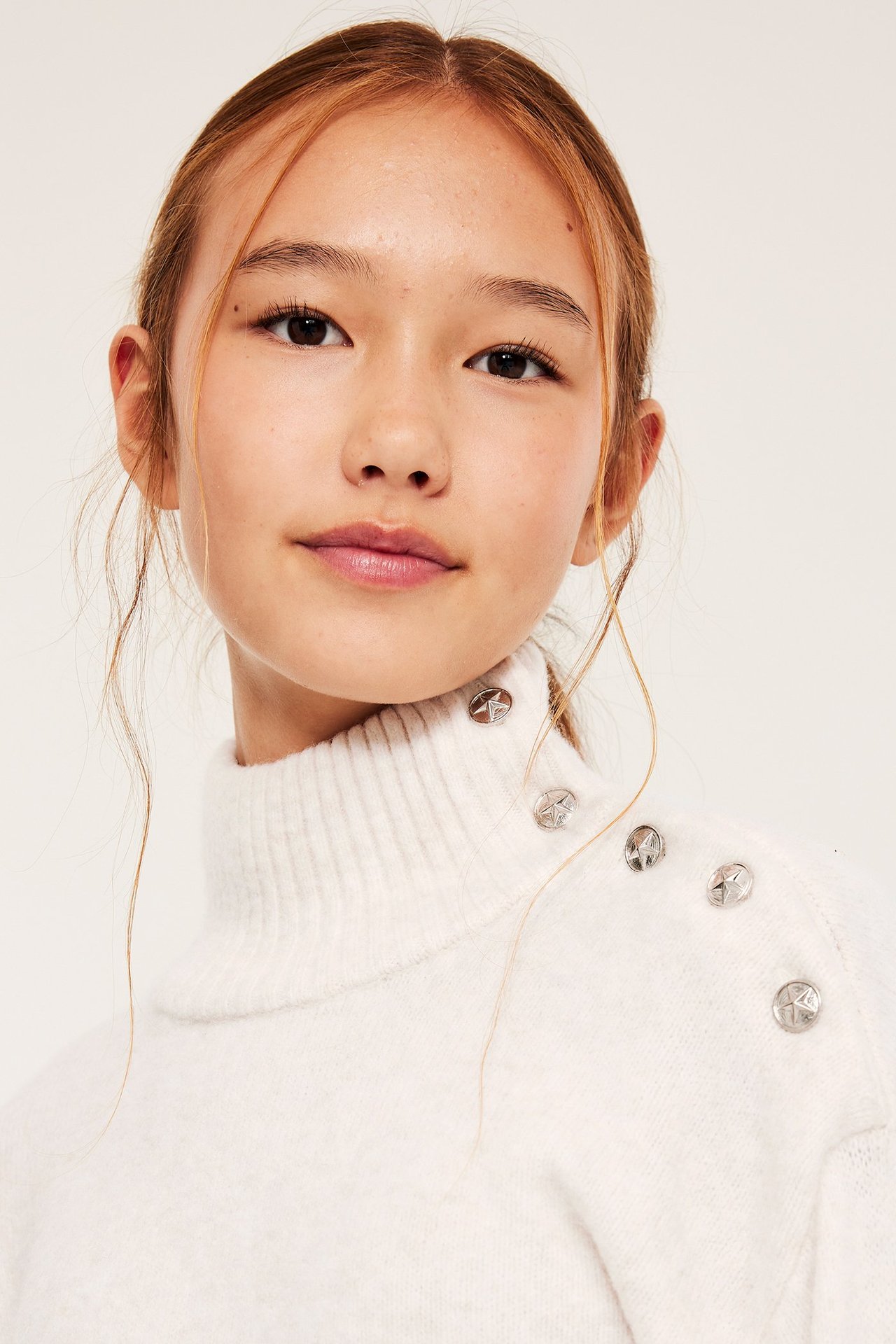 Nuori nainen valkoisessa neulospooloneuleessa koristeellisilla napeilla, etusivu.