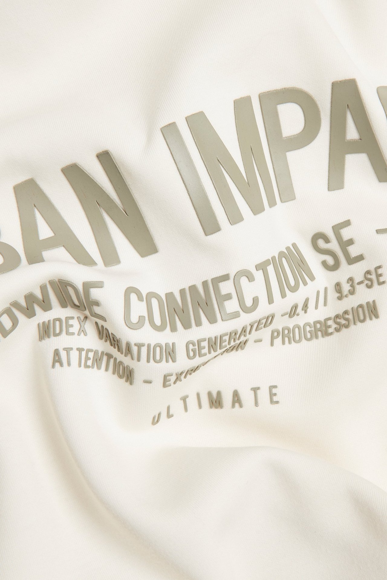 Zbliżenie na off-białą bluzę dresową z interlocku z szarym nadrukiem tekstowym z przodu.