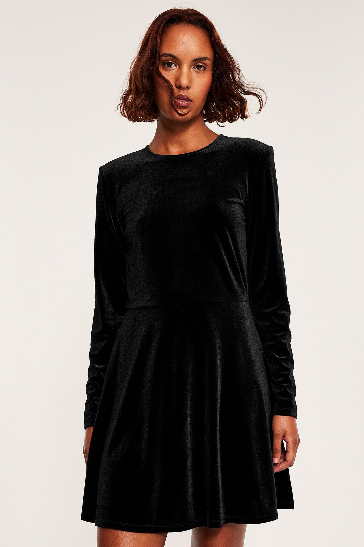 Svart långärmad jerseyklänning i enfärgad design, figursydd och overknäppt.