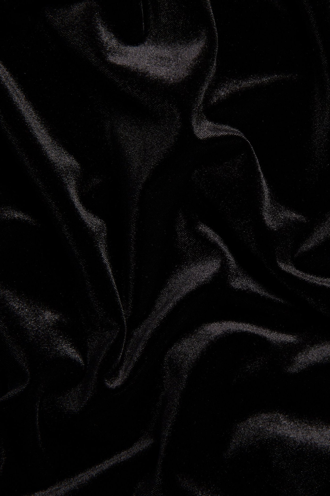 Zbliżenie na czarny dżersej na sukienkę, pokazujące miękkie, jednolite fałdy.