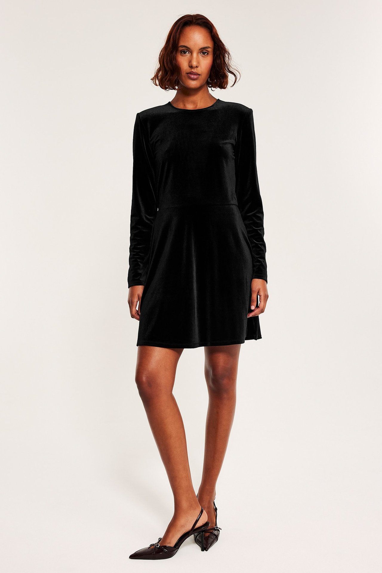 Svart långärmad jerseyklänning med figursydd passform och enfärgad design.