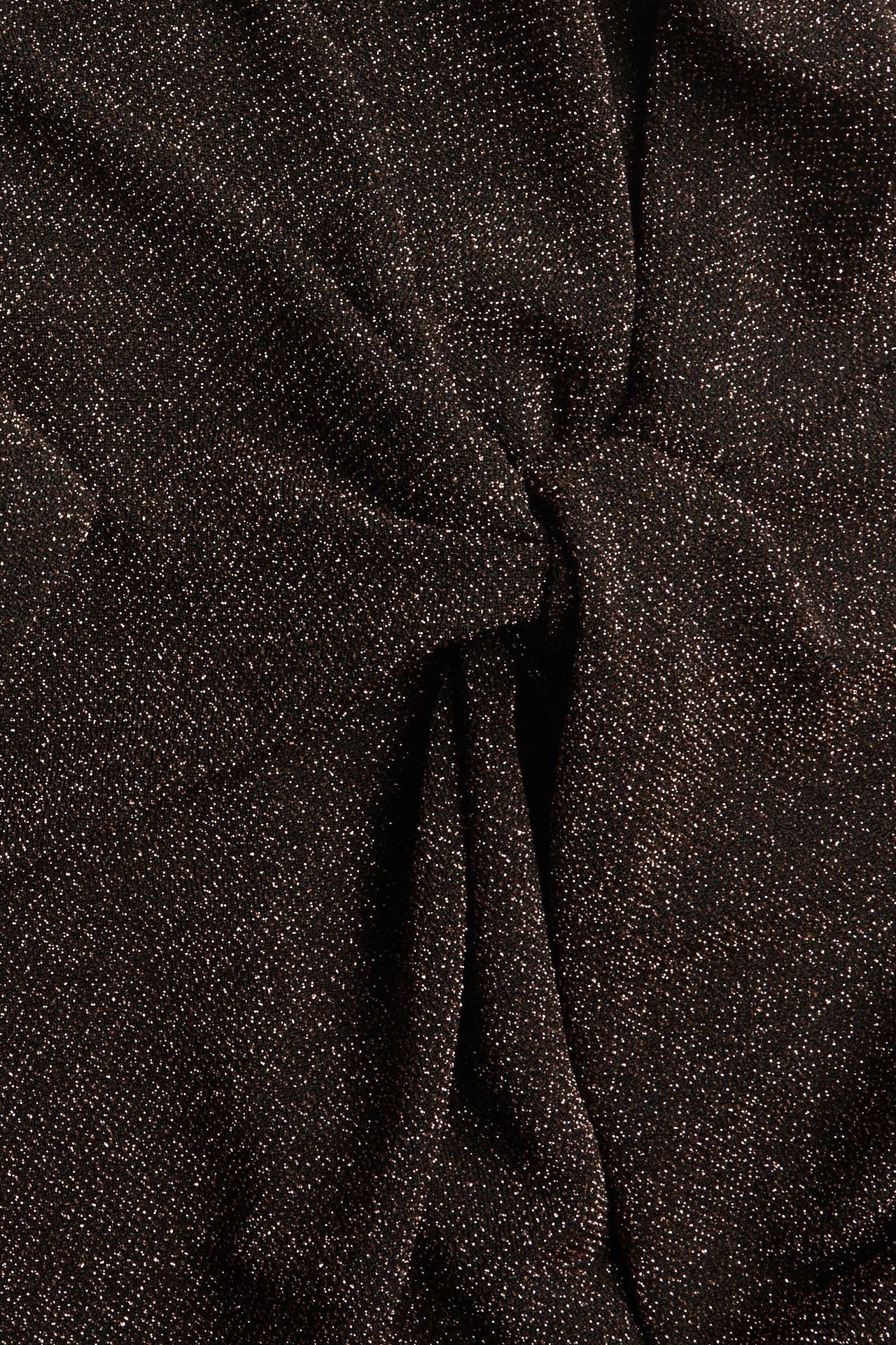 Zbliżenie złotego błyszczącego materiału sukienki lurex z węzłem z przodu.