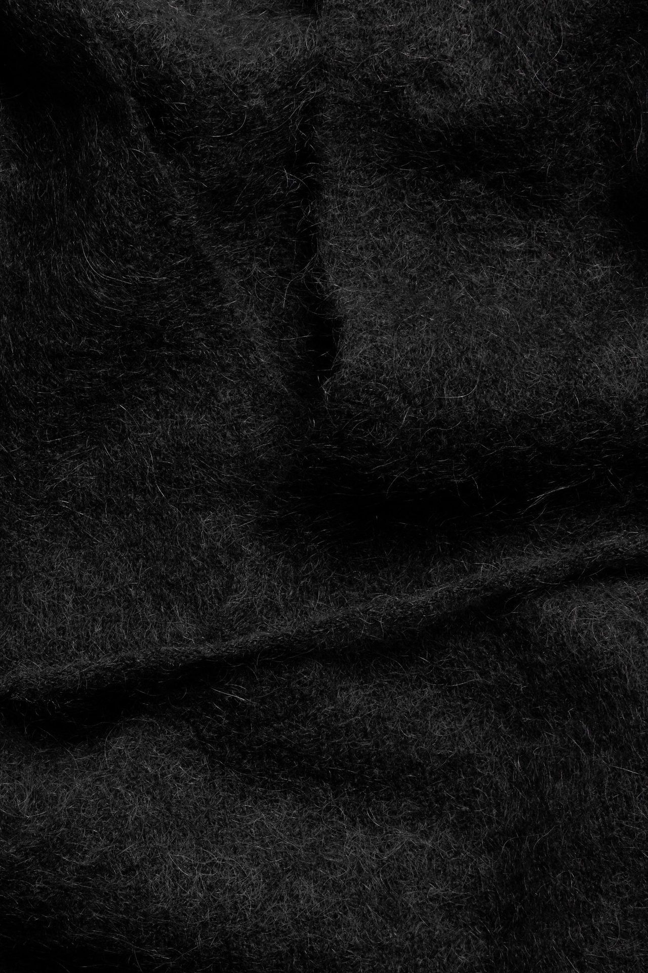 Zbliżenie czarnego, puszystego kardiganu kopertowego z wełny, z fałdami.