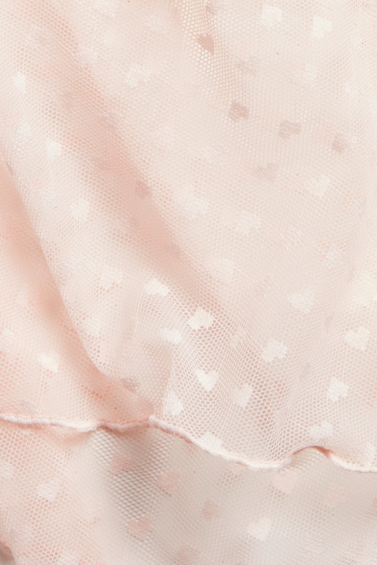 Lähikuva vaaleanpunaisista verkkoshortseista, joissa on hienovarainen sydänkuvio.