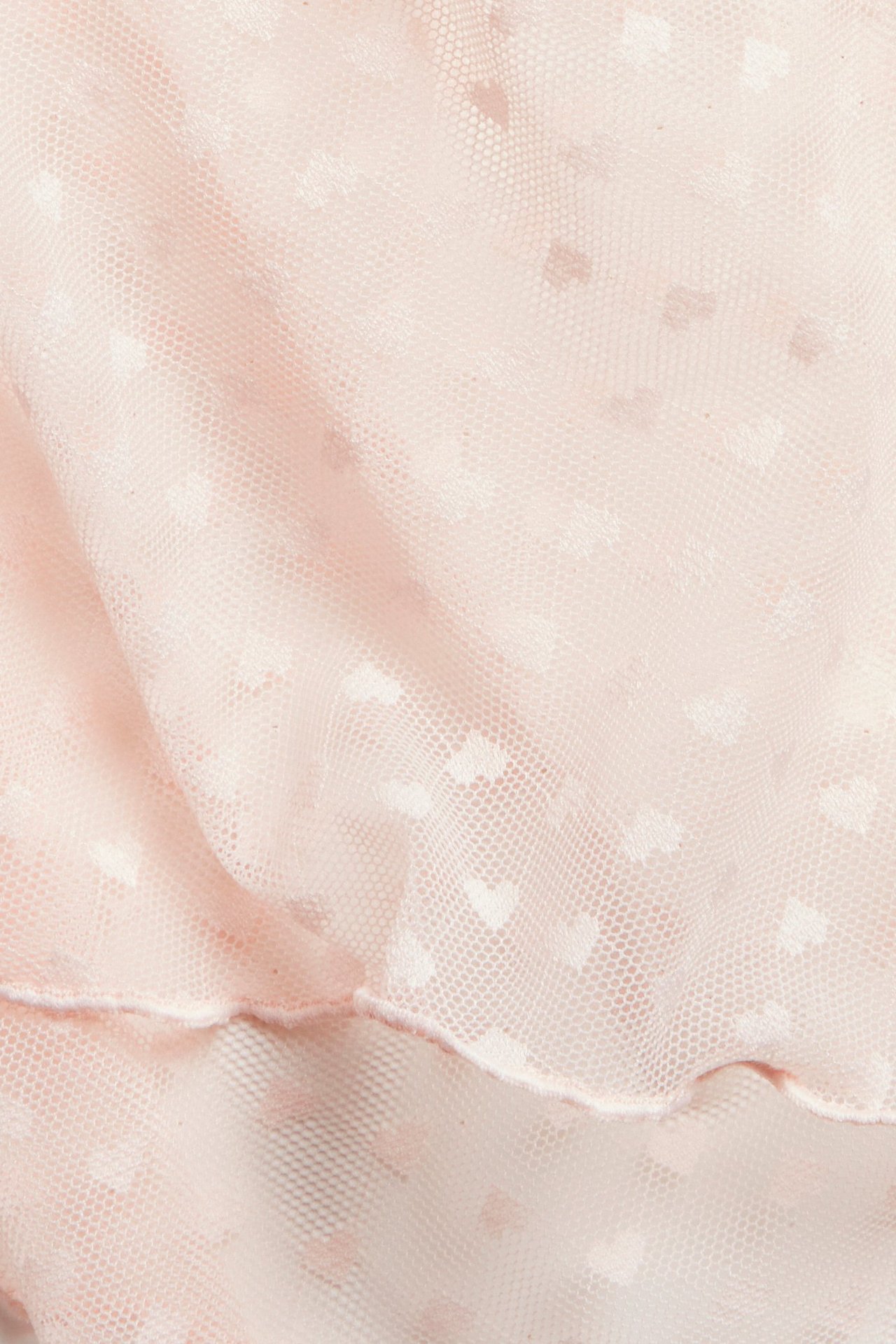 Nærbilde av lys rosa mesh-shorts med et diskret hjerte mønster.