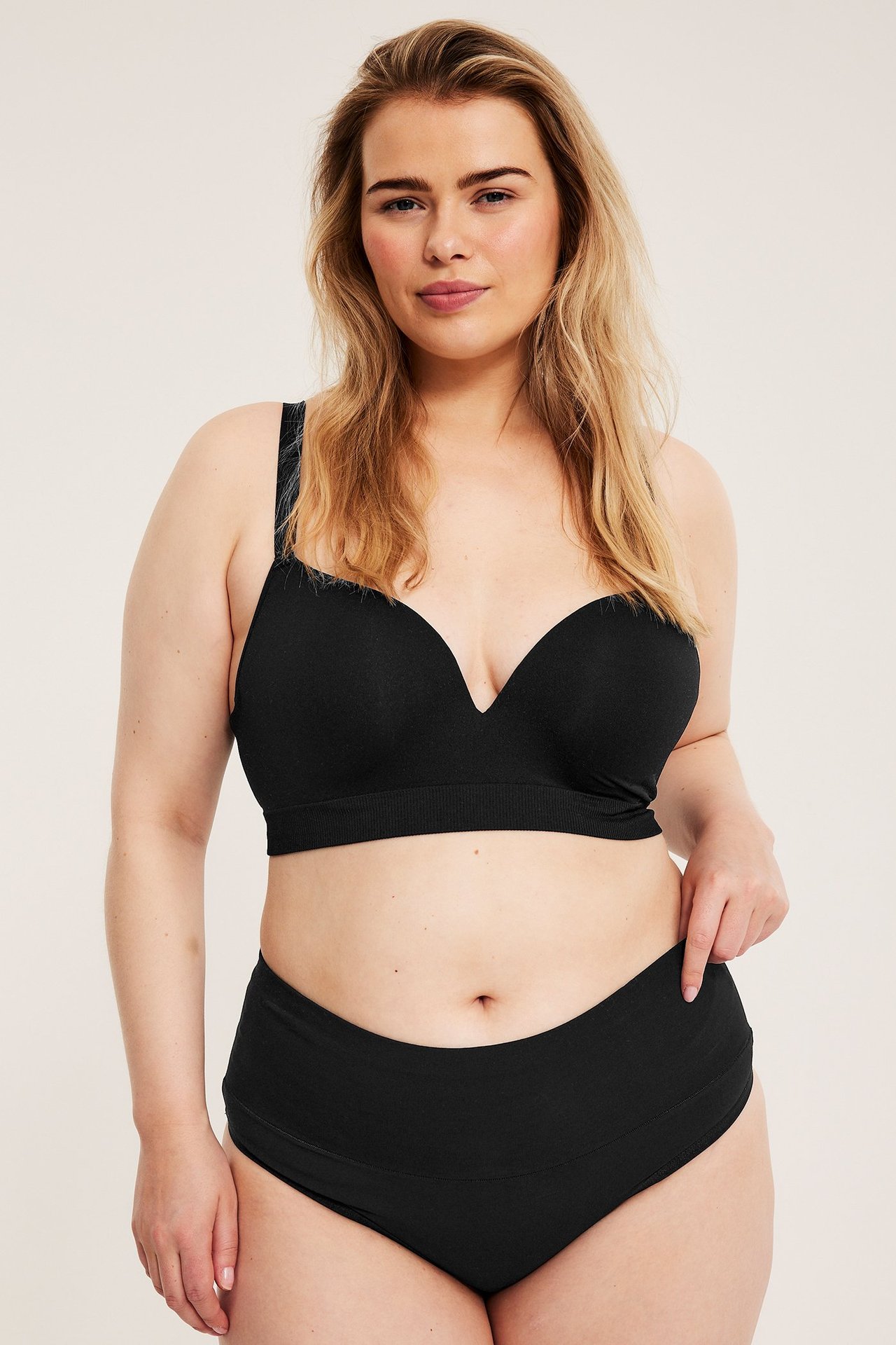 Widok z przodu: kobieta w czarnych bezszwowych figach i pasującym wyściełanym biustonoszu.