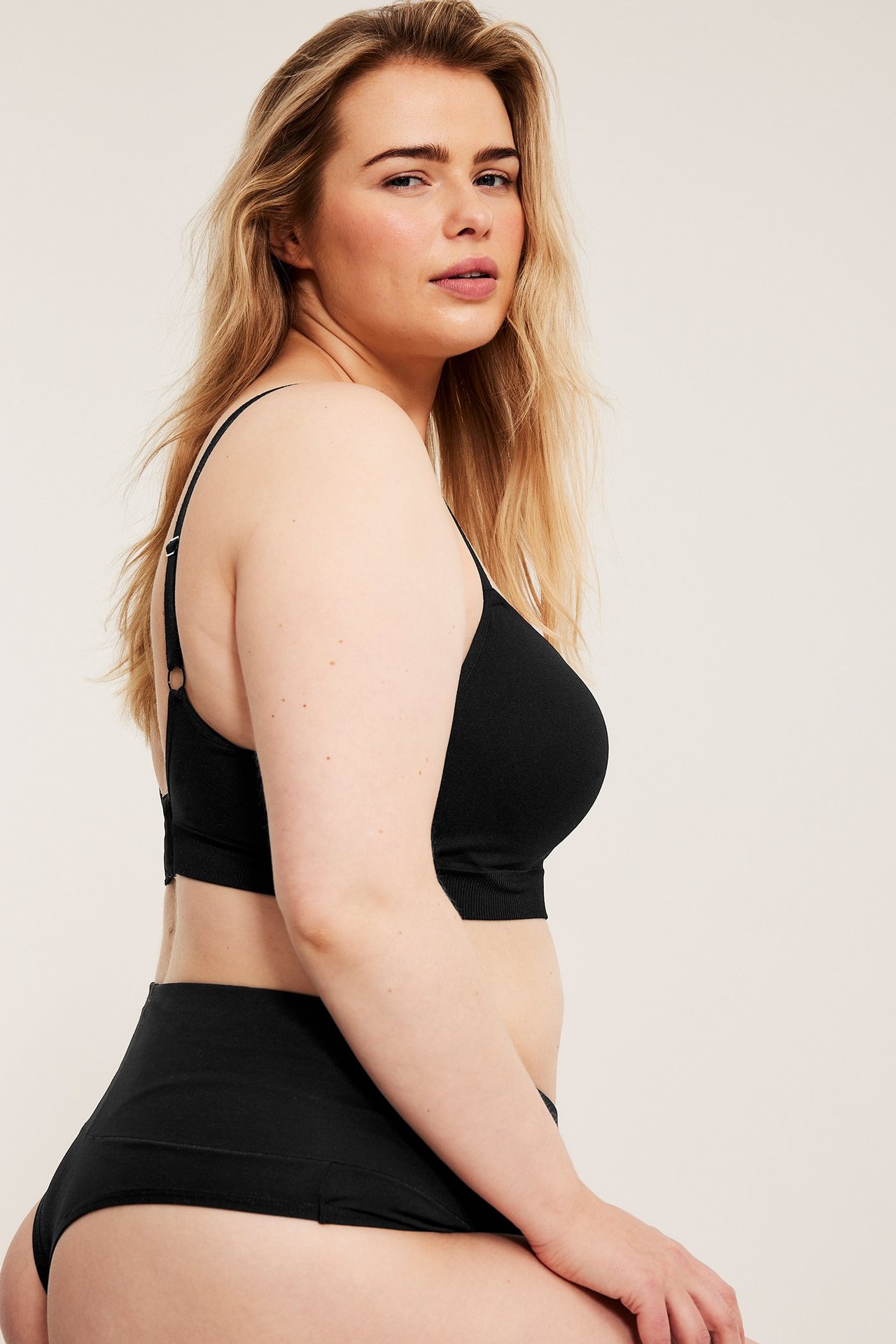 Widok z boku kobiety w czarnych bezszwowych figach z wysokim stanem i pasującym biustonoszu.