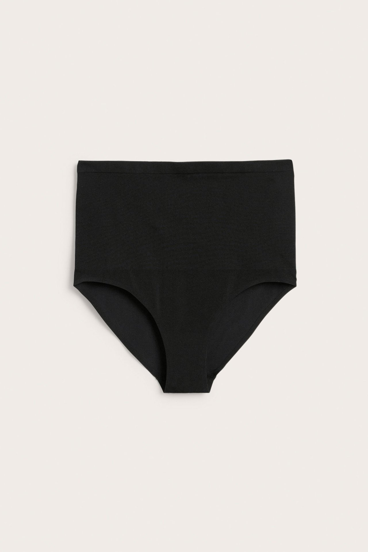 Framifrån, en enfärgad svart sömlös högmidjetrosa av slätt tyg.