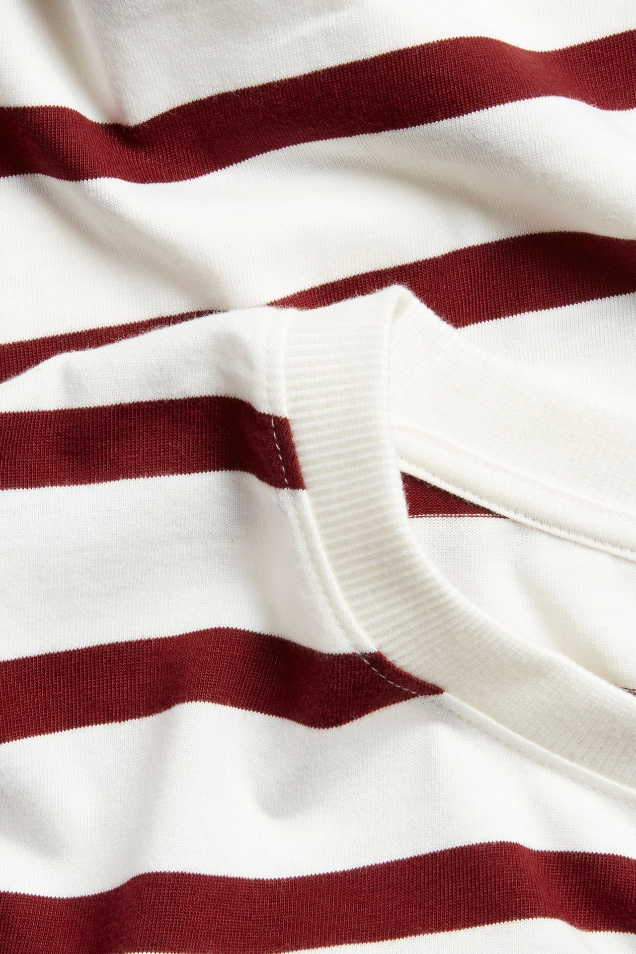Zbliżenie czerwono-białej bluzki bawełnianej w paski z prążkowanym okrągłym dekoltem.