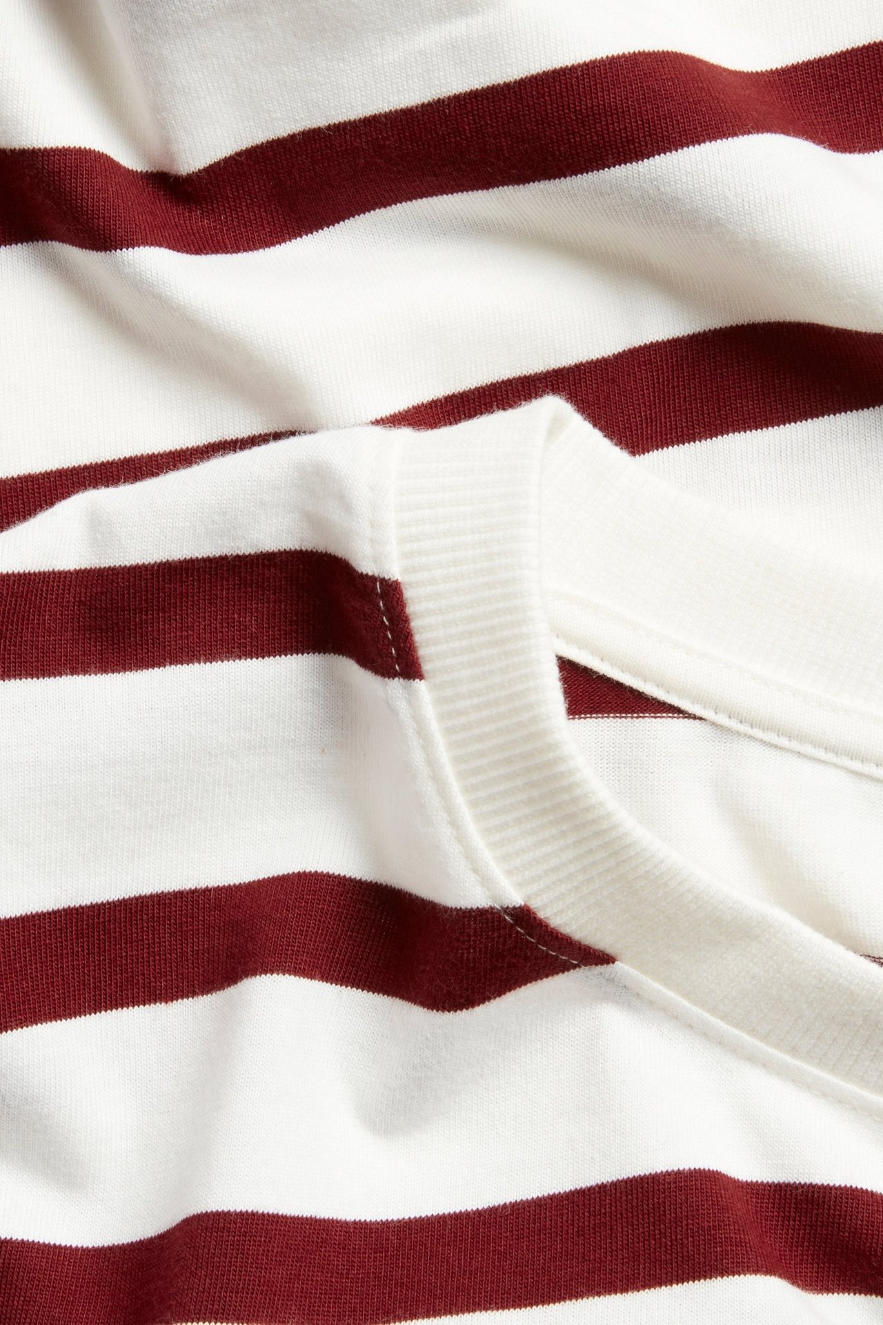 Zbliżenie czerwono-białej bluzki bawełnianej w paski z prążkowanym okrągłym dekoltem.