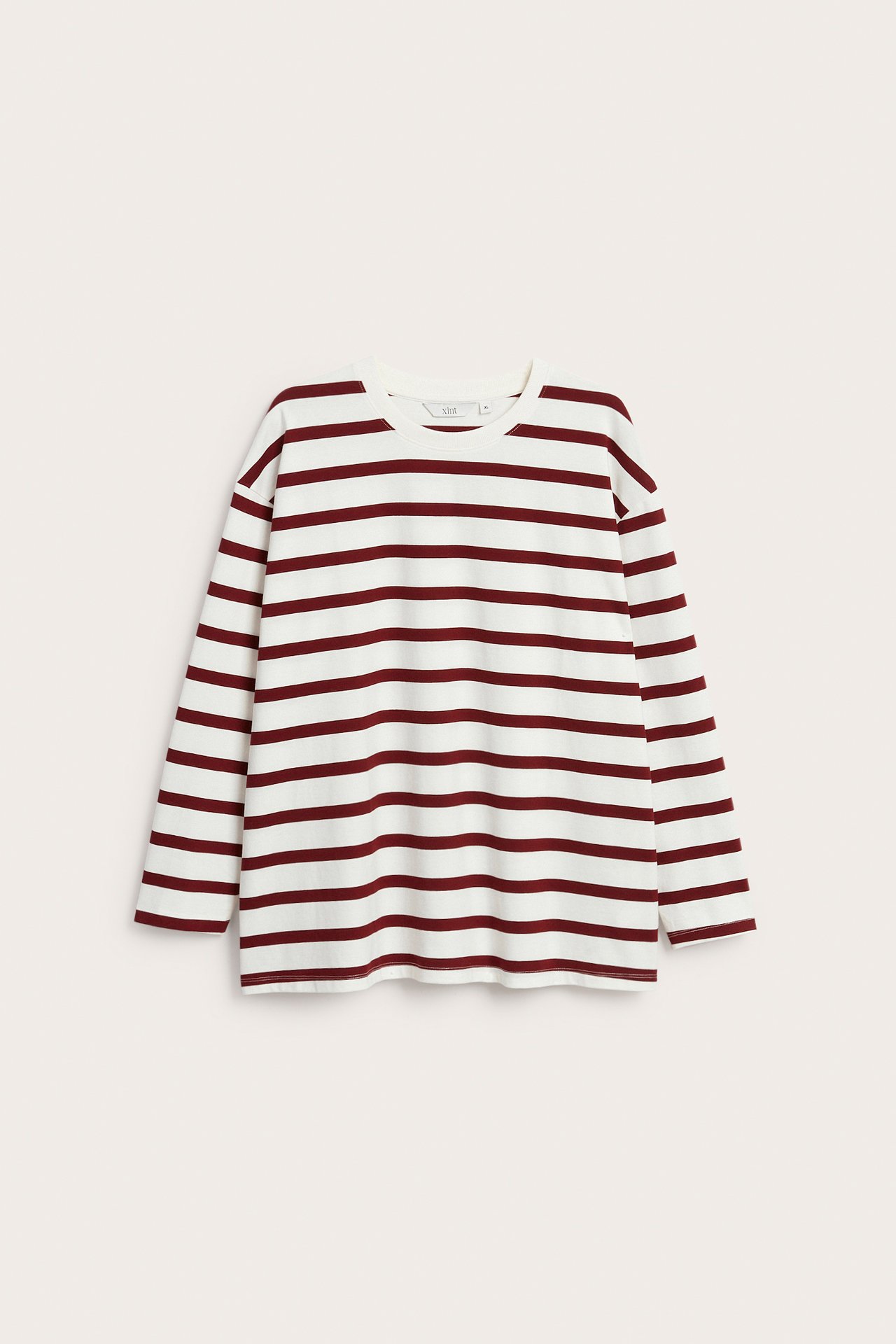 Forfra: løs hvit langermet bomullstopp med røde horisontale striper og rund hals.