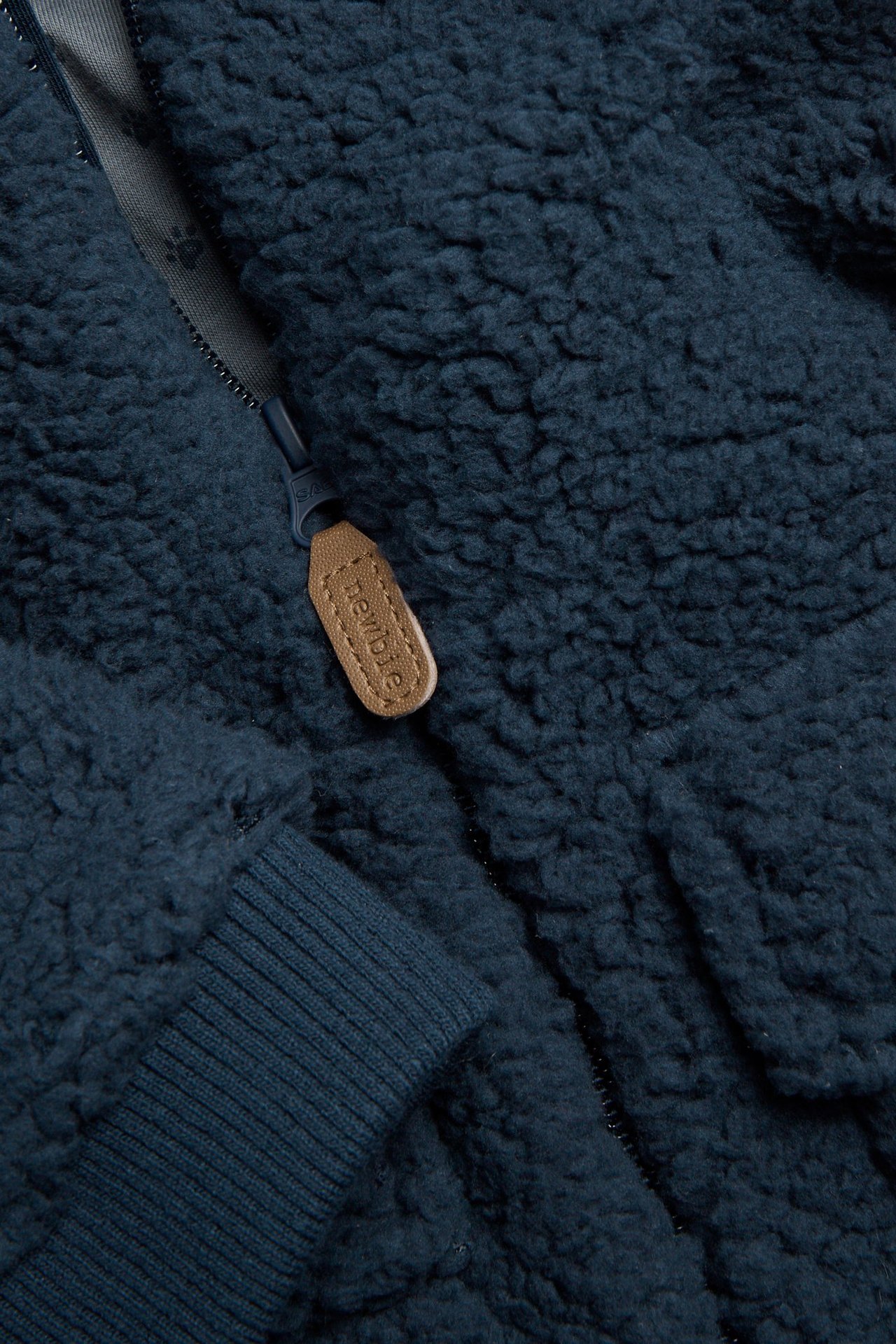 Lähikuva tummansinisestä fleecetakista, jossa vetoketju ja resorihihansuu.
