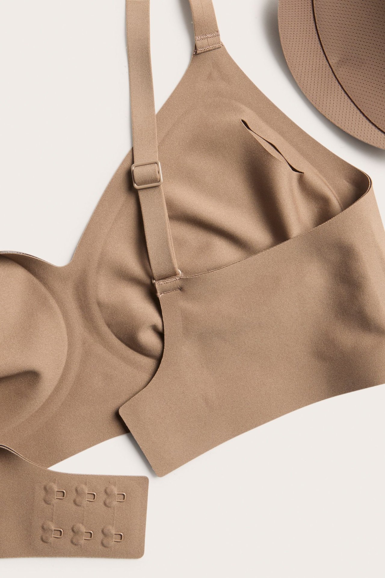 Närbild av en brun bygellös bh med justerbara axelband, hak- och hyskknäppning samt en synlig uttagbar pad.