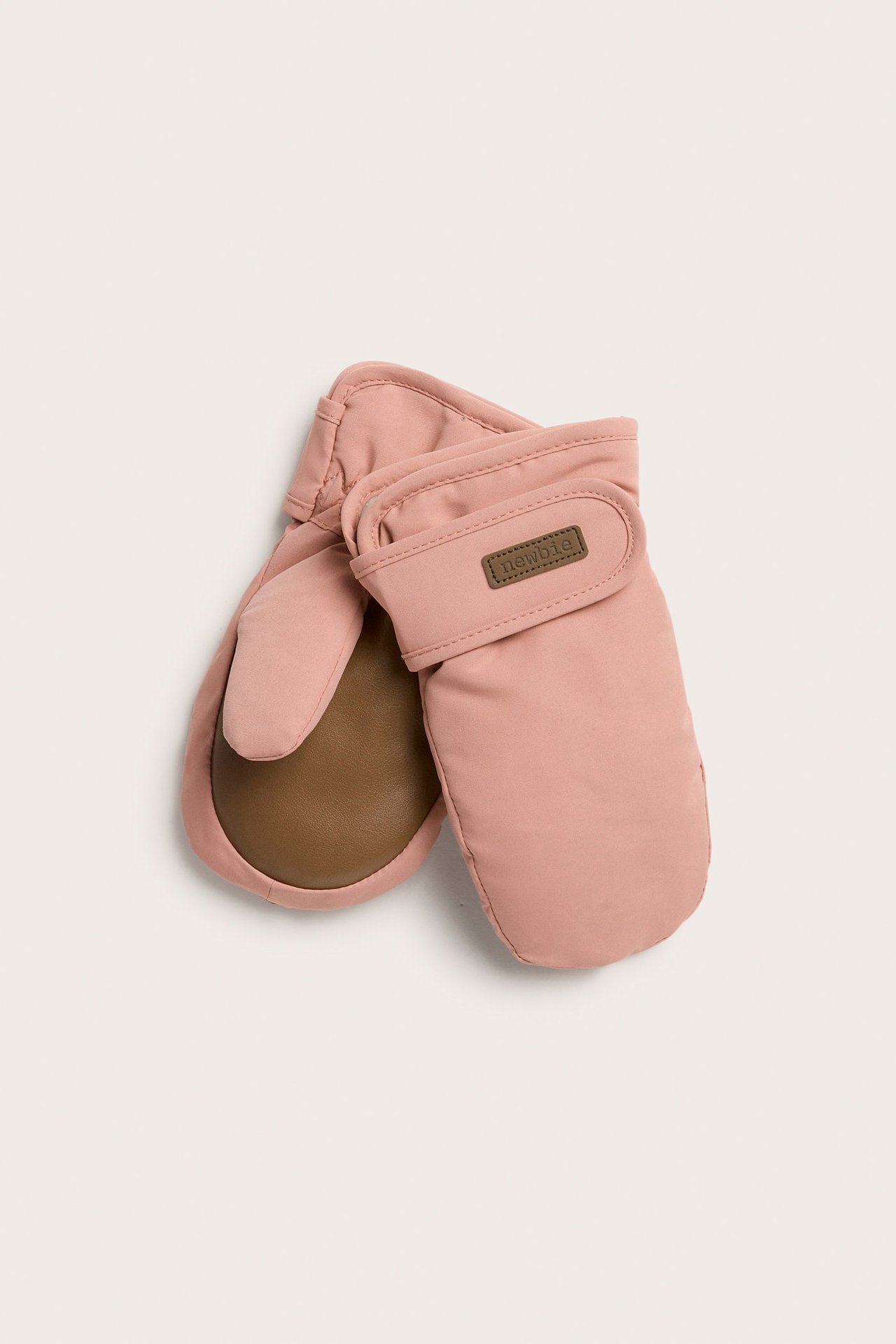 Ylhäältä näkymä, vaaleanpunaiset topatut rukkaset ruskeilla kämmenillä ja tarranauhoilla hihansuissa.