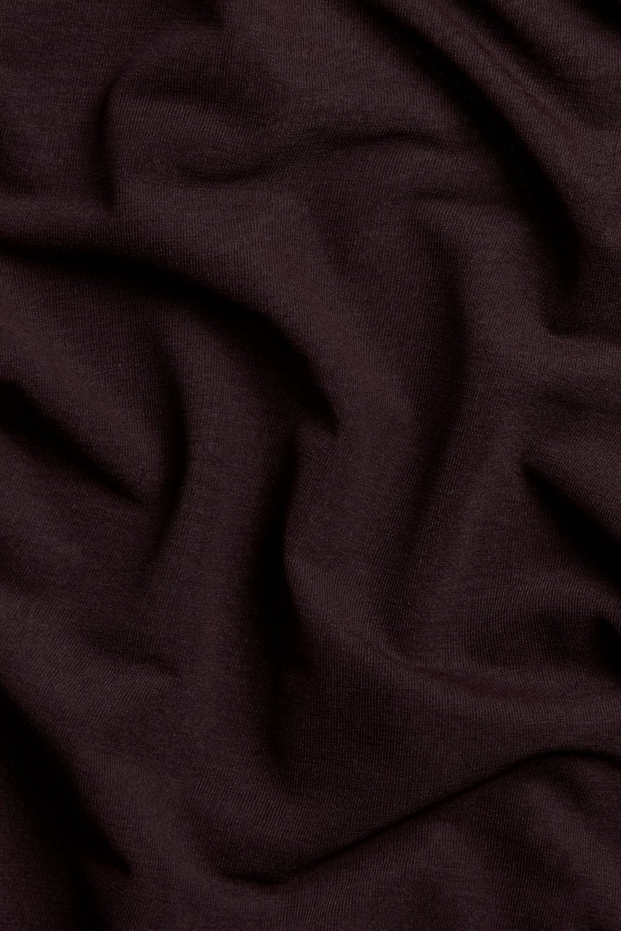 Zbliżenie na jednolity bordowy materiał siateczkowy z poliestru z miękkimi fałdami.