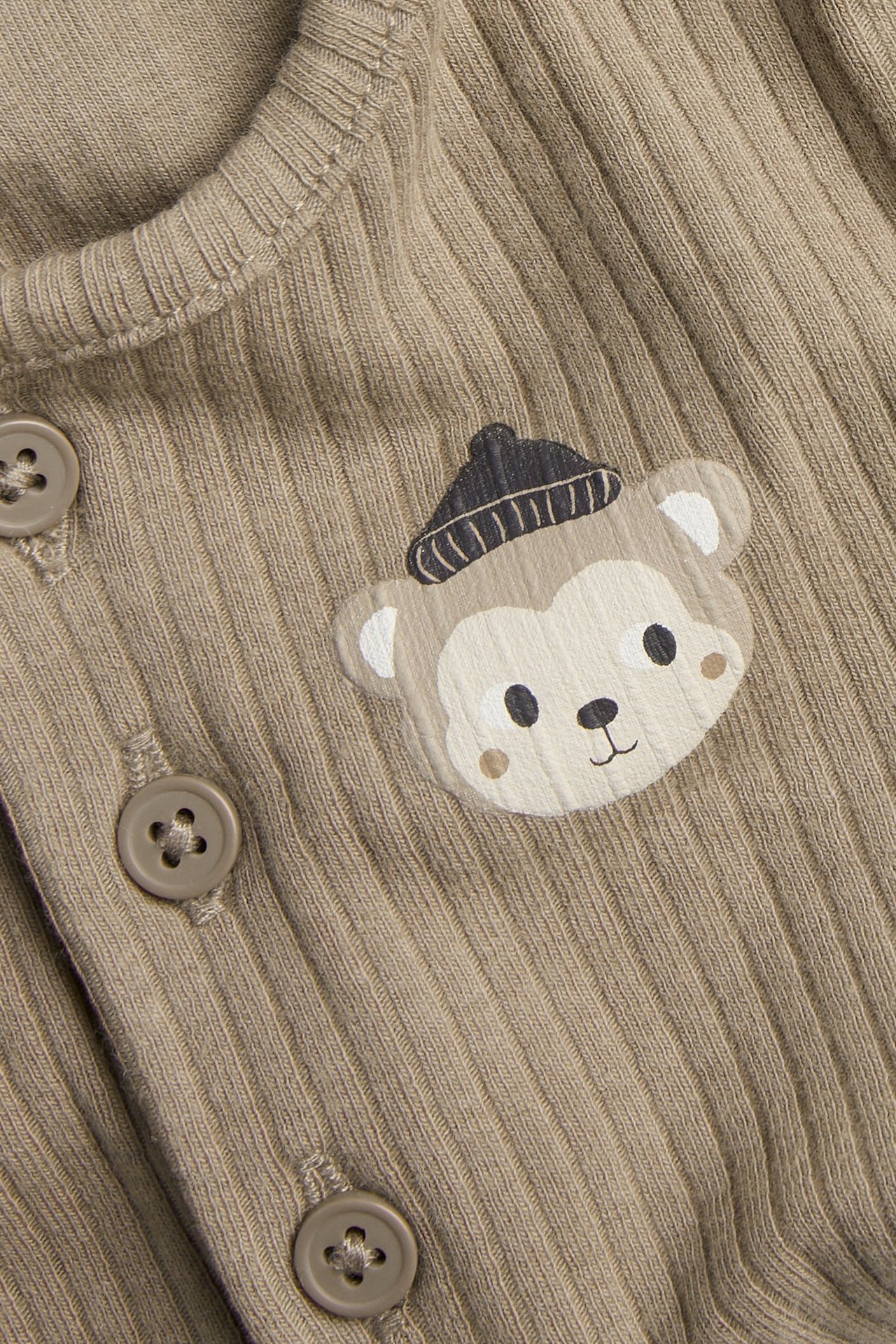 Nærbilde forfra av en brun ribbet babybody med apeprint og brune knapper.