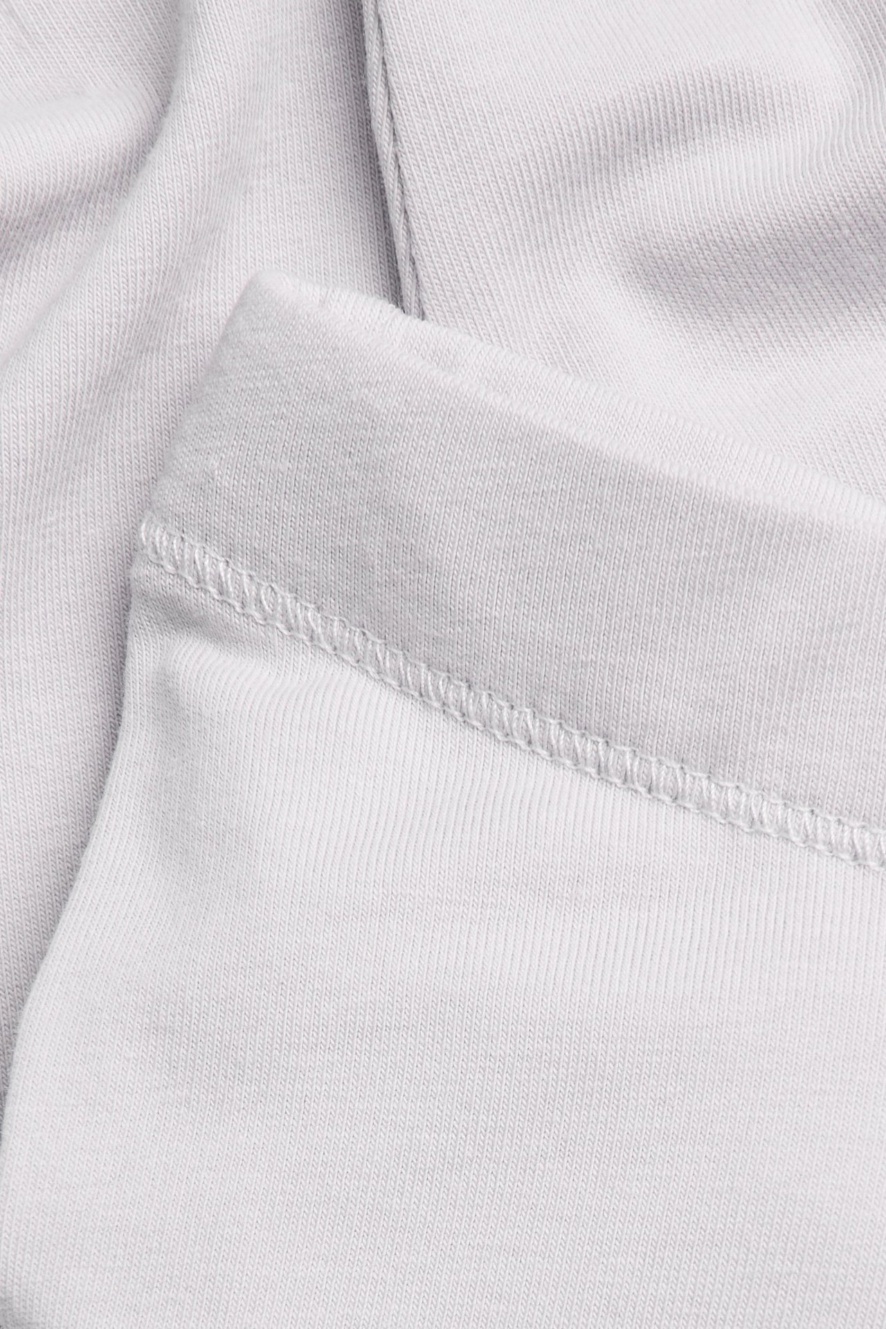 Nærbilde av lys lilla ribbestrikkede leggings, viser elastisk linning med sømdetaljer.